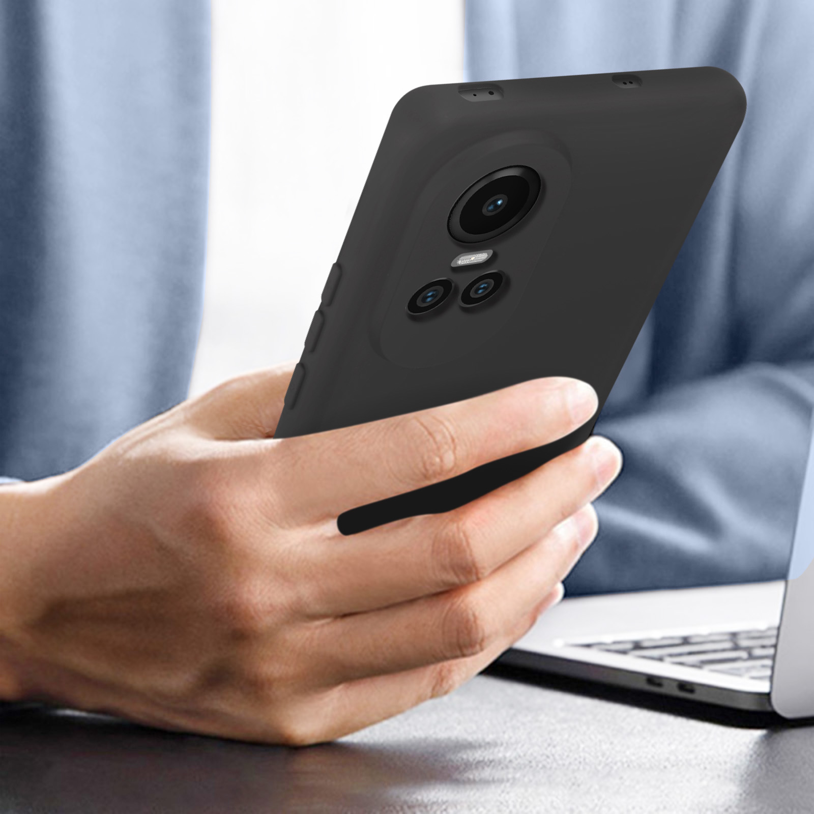 Una persona tiene in mano un telefono nero. Il telefono ha una fotocamera e uno sfondo scuro. La persona indossa il blu.