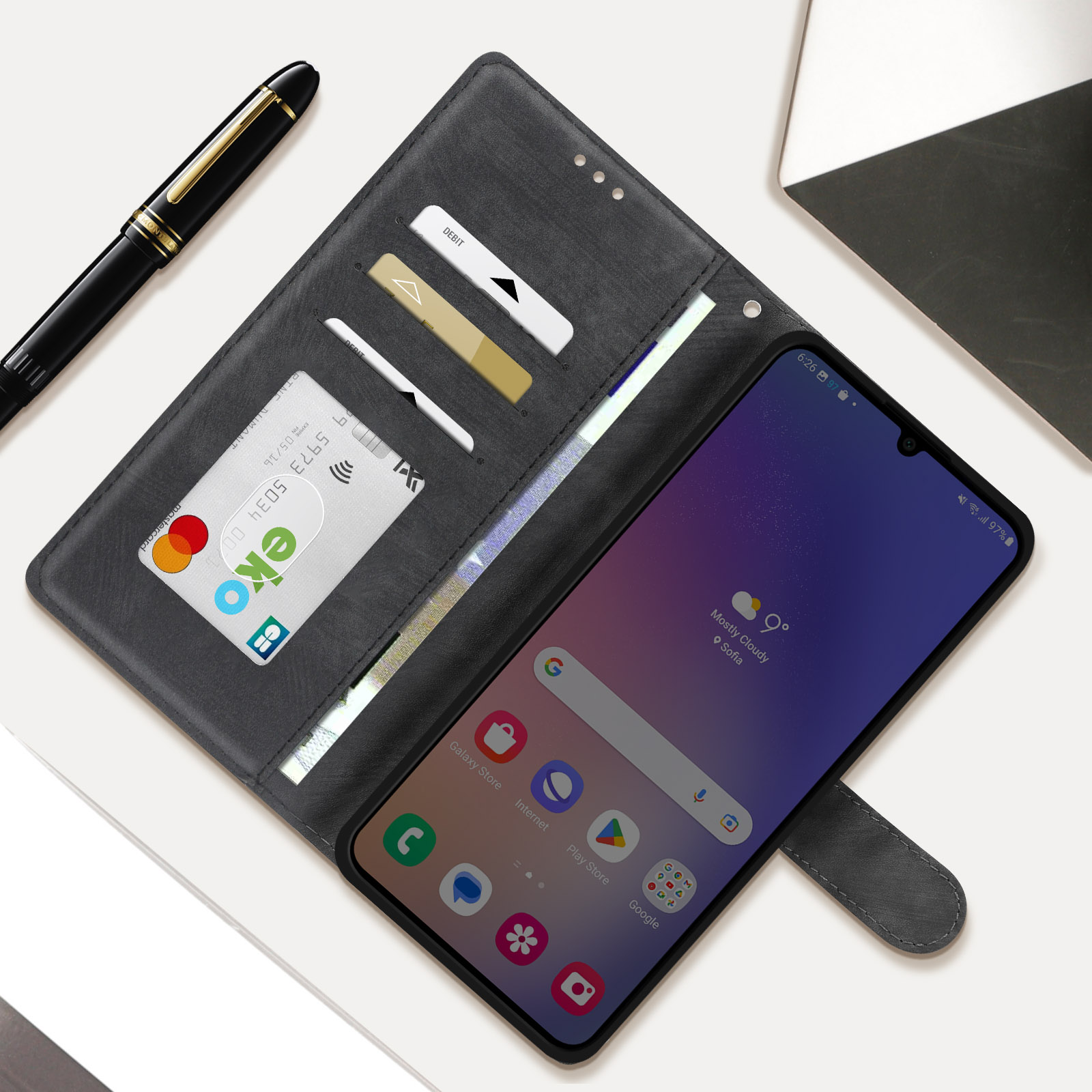Schwarze Handyhülle offen mit Smartphone, Kreditkarten und Stift. Das Telefon zeigt Zeit.