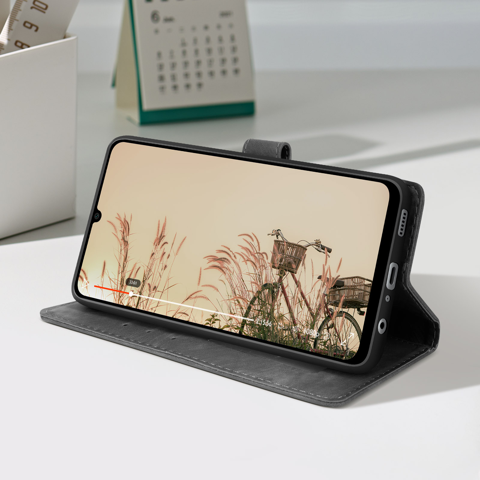 Telefon in grauem Case, zeigt Video auf dem Bildschirm, auf weißem Tisch.
