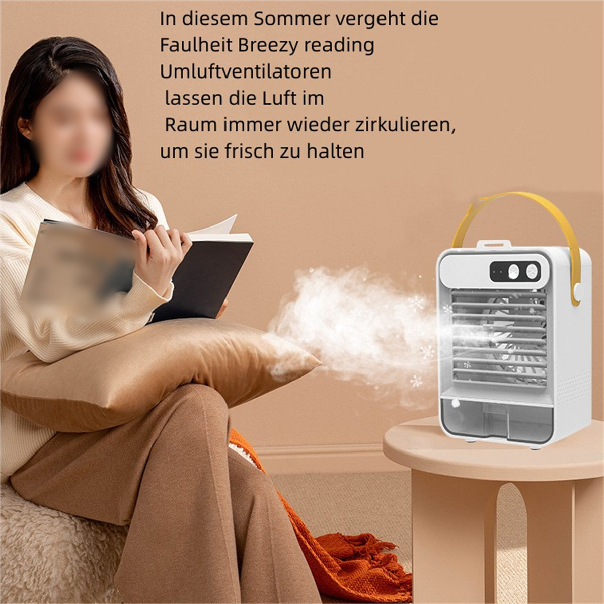 Eine Person liest ein Buch neben einem kleinen weißen Luftkühler auf einem Tisch.