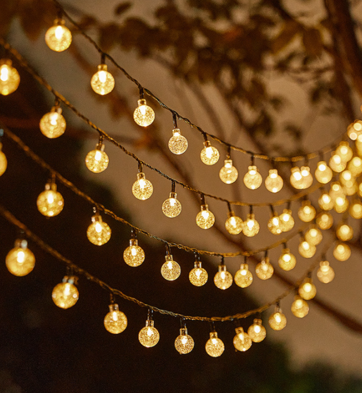 Lichterkette hängt, warm gelb leuchtend. Hintergrund ist dunkel und verschwommen.
