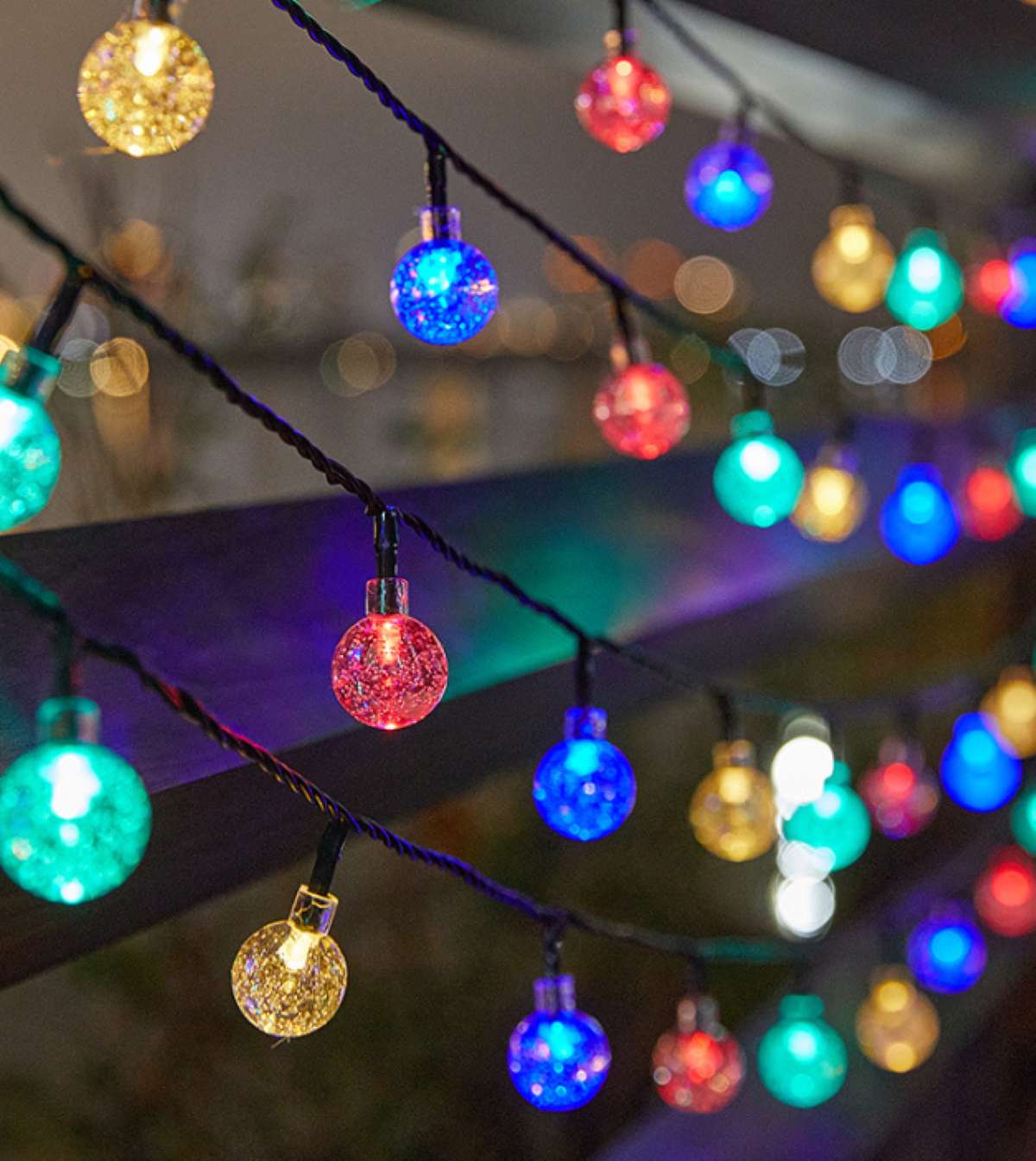 Lichterketten mit bunten, leuchtenden Glühbirnen hängen im Freien und schaffen eine festliche Szene.