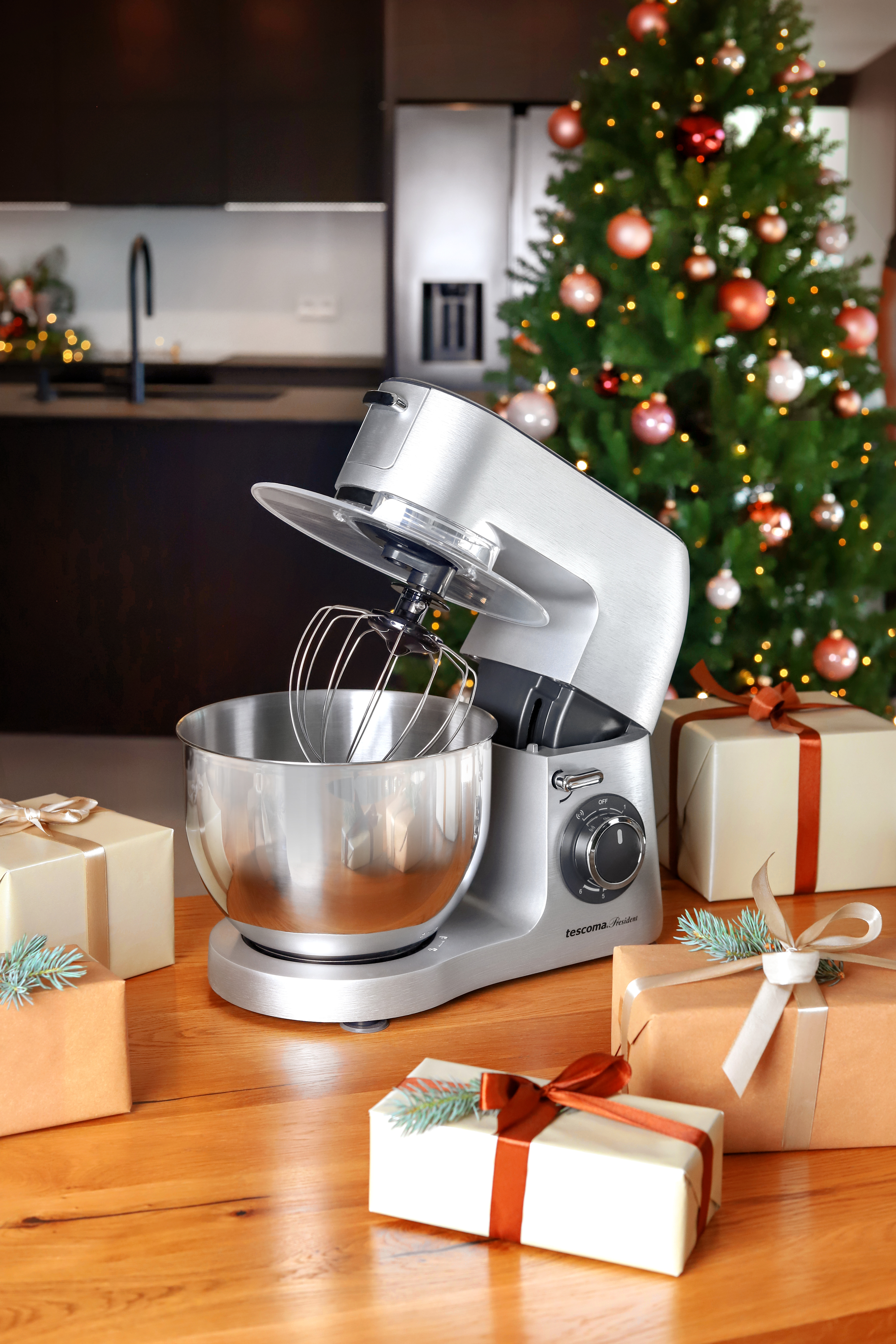 Silberner Küchenmixer auf einem Tisch. Geschenke und Weihnachtsbaum im Hintergrund.