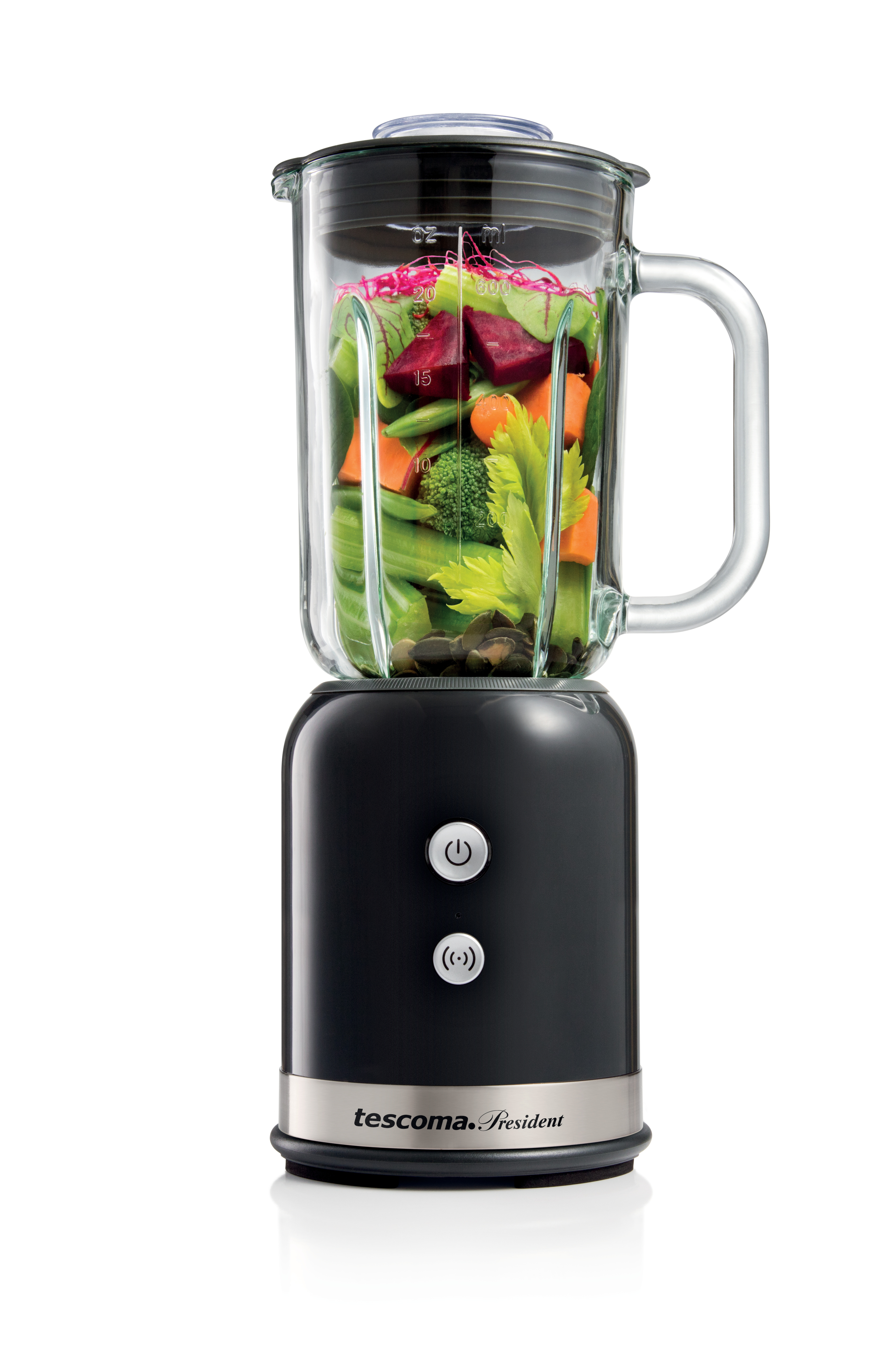 Schwarzer Mixer mit Glasbehälter, gefüllt mit Gemüse. Karotten, Sellerie, Rüben sichtbar. Weißer Hintergrund.