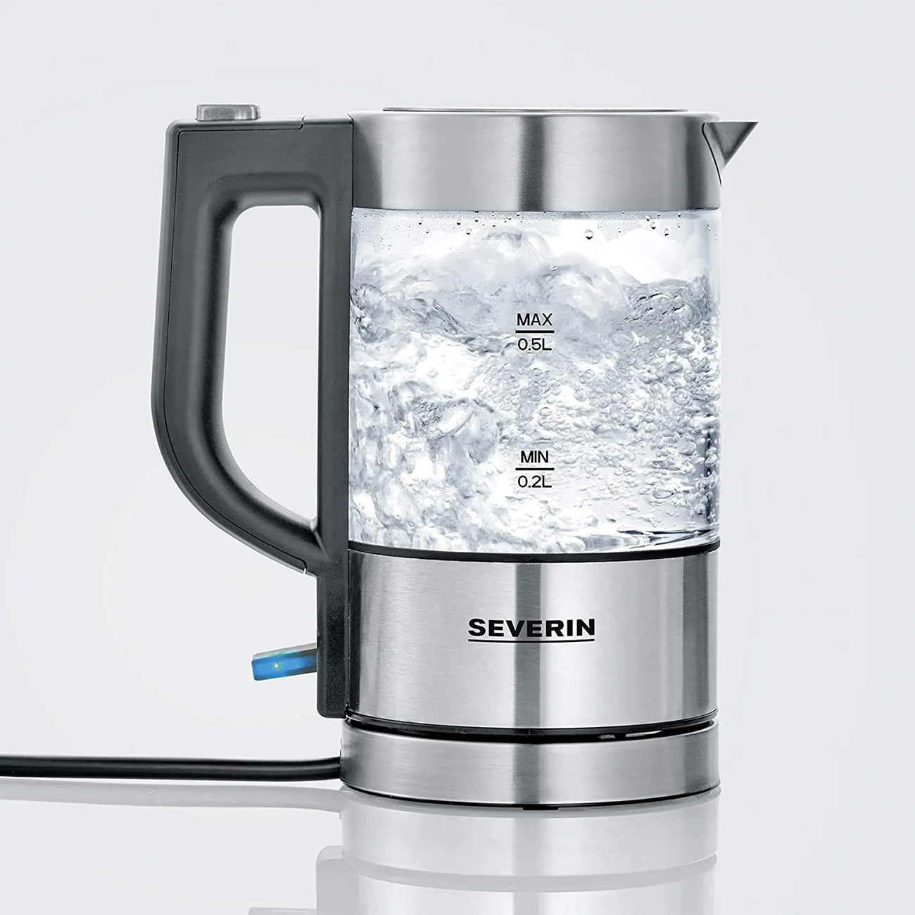 Przezroczysty szklany czajnik elektryczny z wrzącą wodą, czarnym uchwytem i podstawą, białe tło.