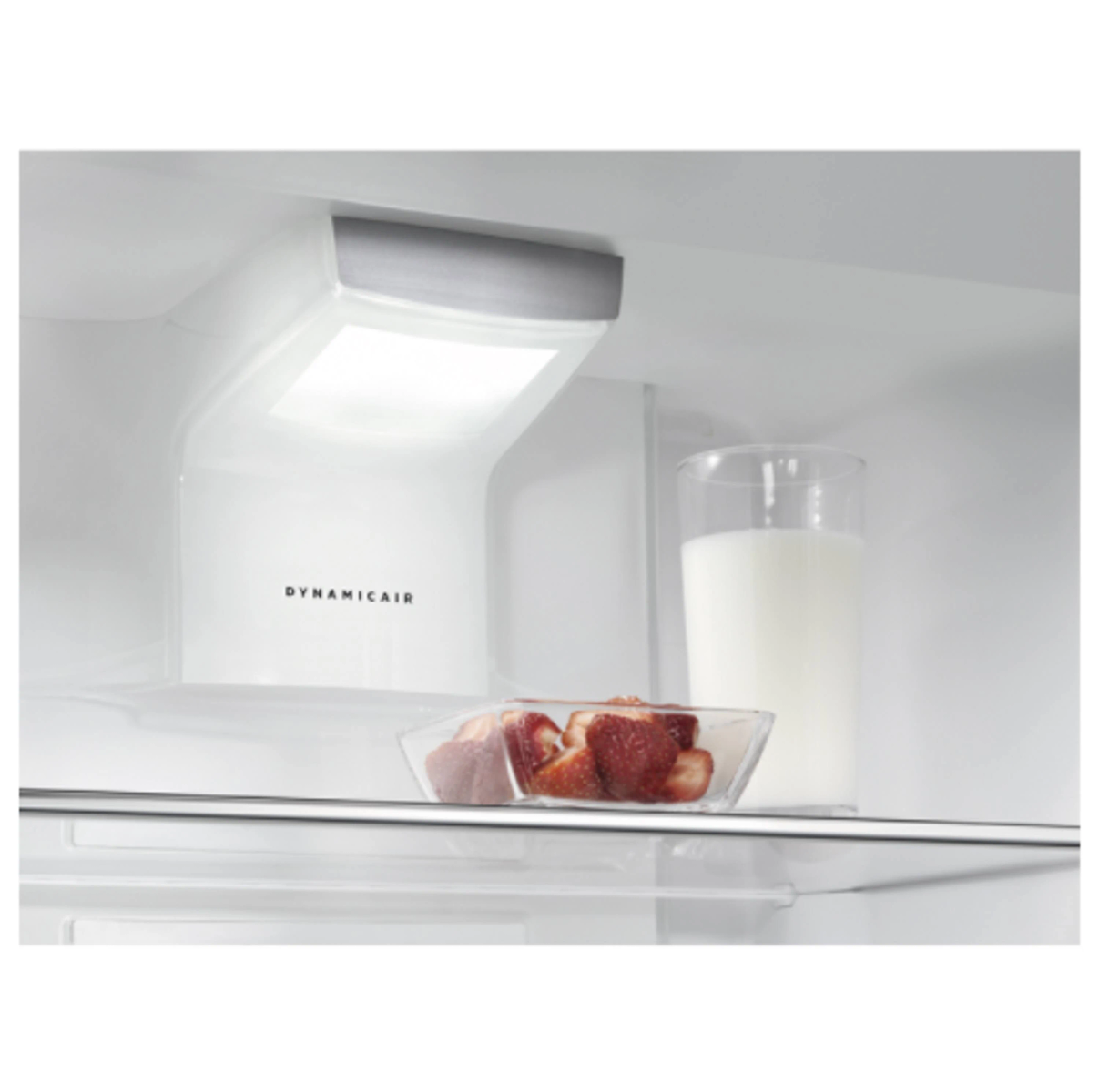 Binnenkant van een koelkast, licht boven een schaal aardbeien en een glas melk.