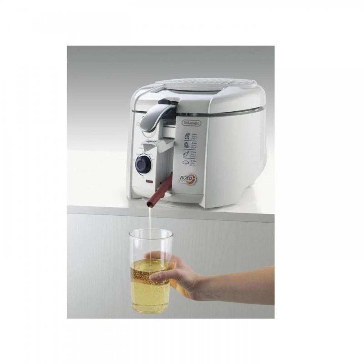 Biała frytkownica z olejem wlewanym do szklanki. Ręka trzyma szklankę.