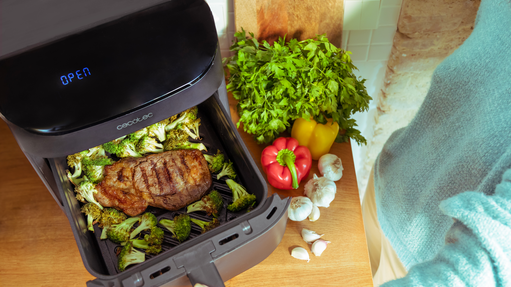 Airfryer met biefstuk en groenten, open, houten oppervlak.