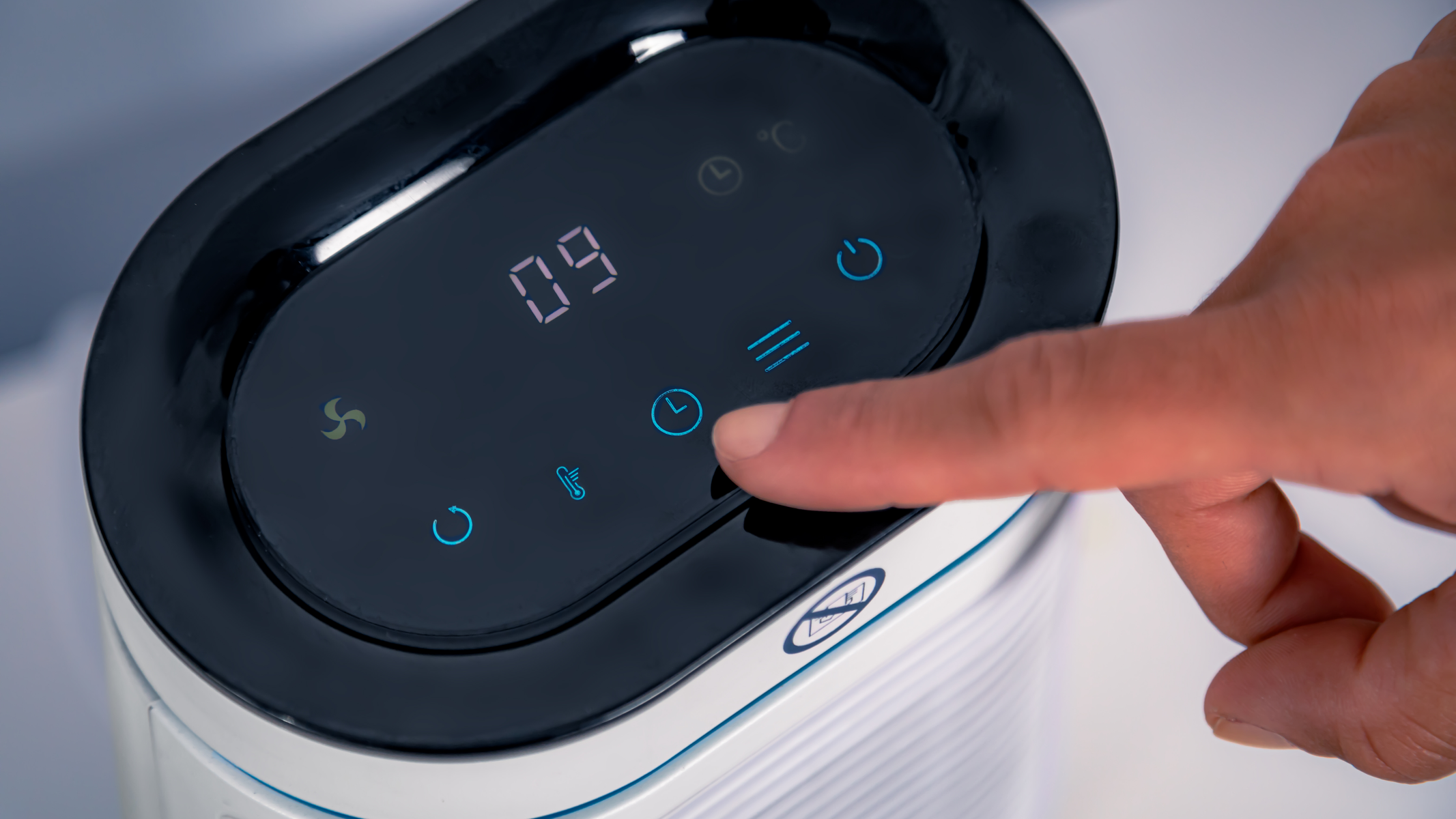 La mano di una persona che tocca un display digitale su un elettrodomestico bianco.