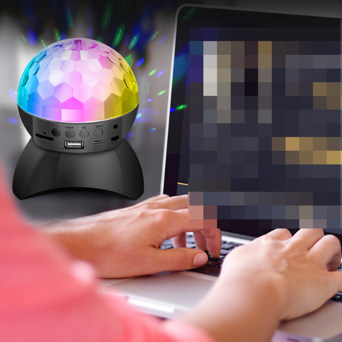 Ein Discokugel-Lautsprecher neben einem Laptop, der farbiges Licht reflektiert.