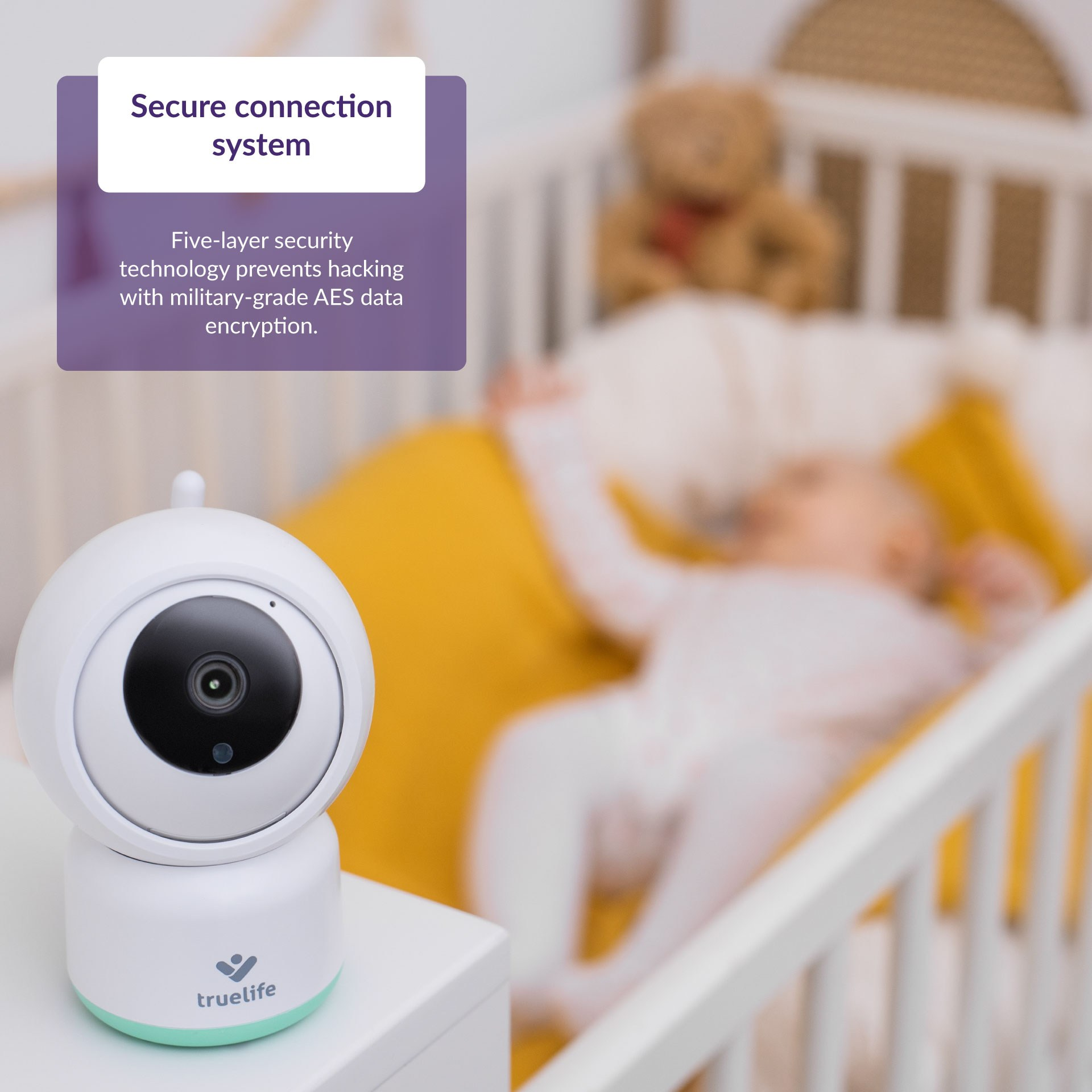 Ein Babyphone steht auf einem Tisch. Ein Baby liegt im verschwommenen Hintergrund in einem Kinderbett.
