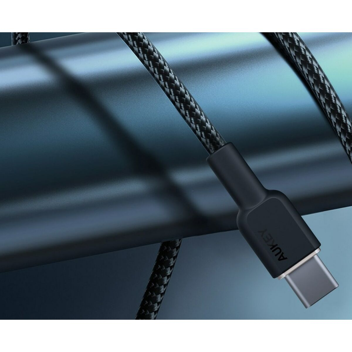 Czarny kabel USB-C z logo AUKEY. Kabel jest pleciony. Tło jest ciemnoniebieskie.