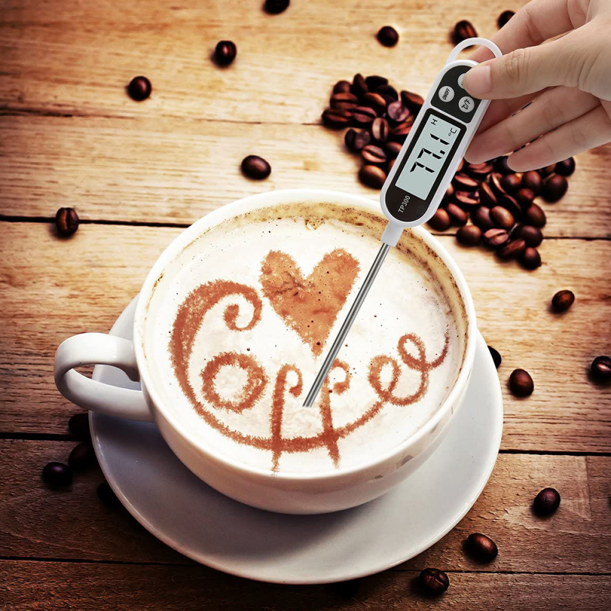 Hand, die ein Thermometer in Kaffee mit Herzdesign hält.