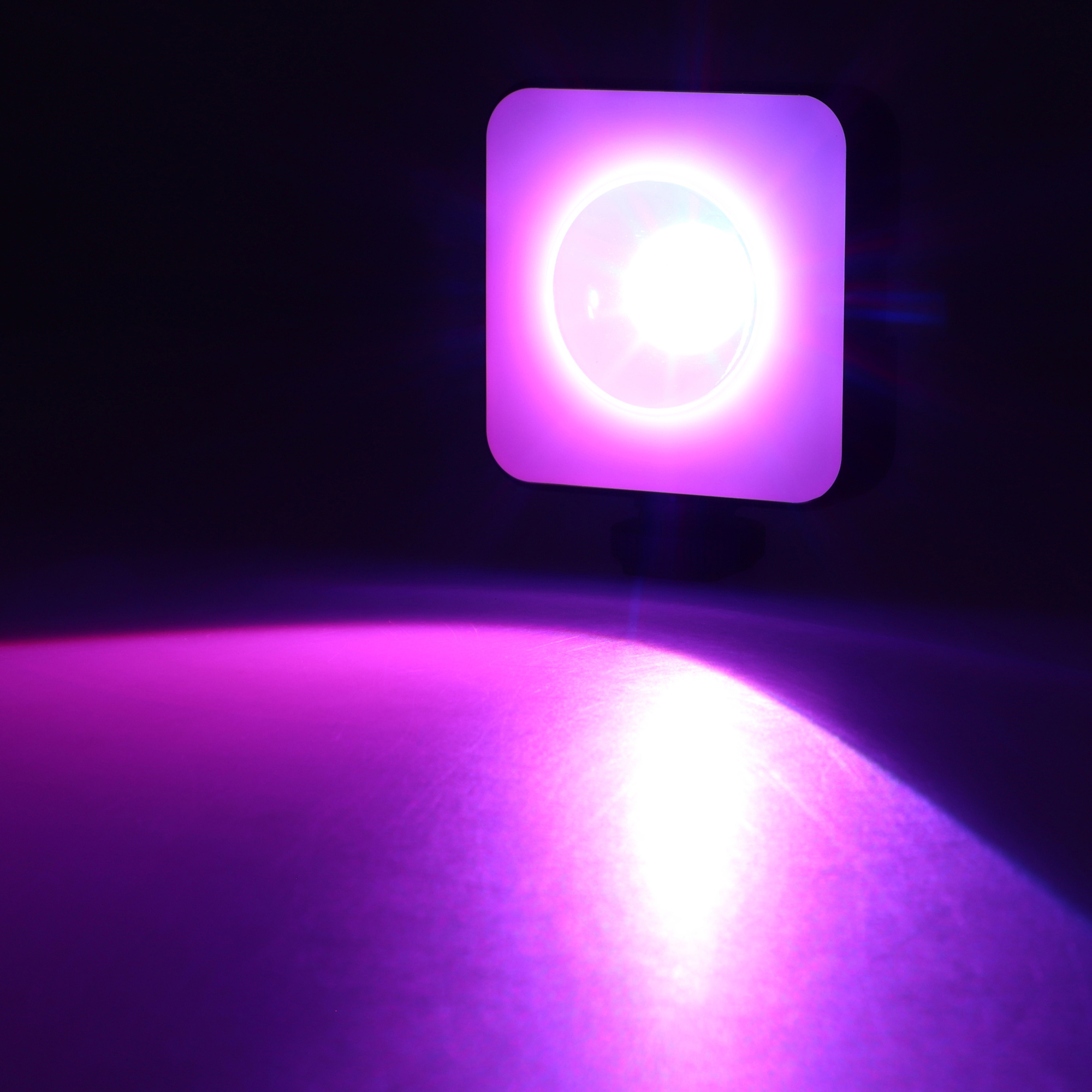Ein violettes Licht, das auf eine Oberfläche scheint. Dunkler Hintergrund.