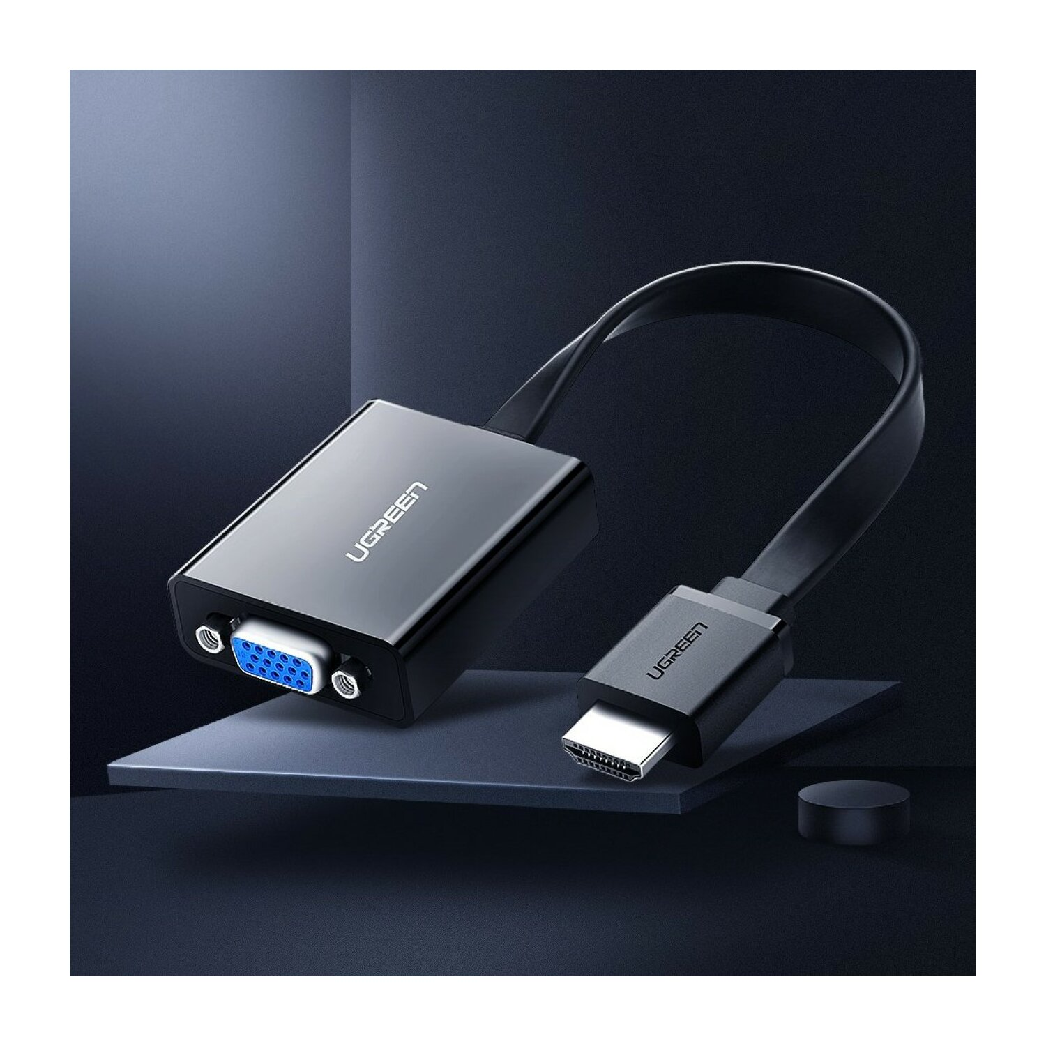 Czarny adapter UGREEN. Jeden koniec to VGA, drugi to HDMI. Jest na ciemnoniebieskiej powierzchni.
