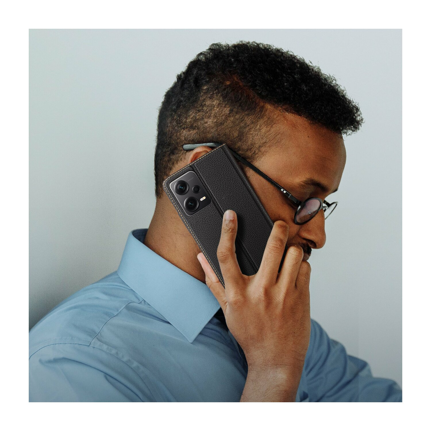Mann mit Brille telefoniert, schwarze Handyhülle sichtbar.