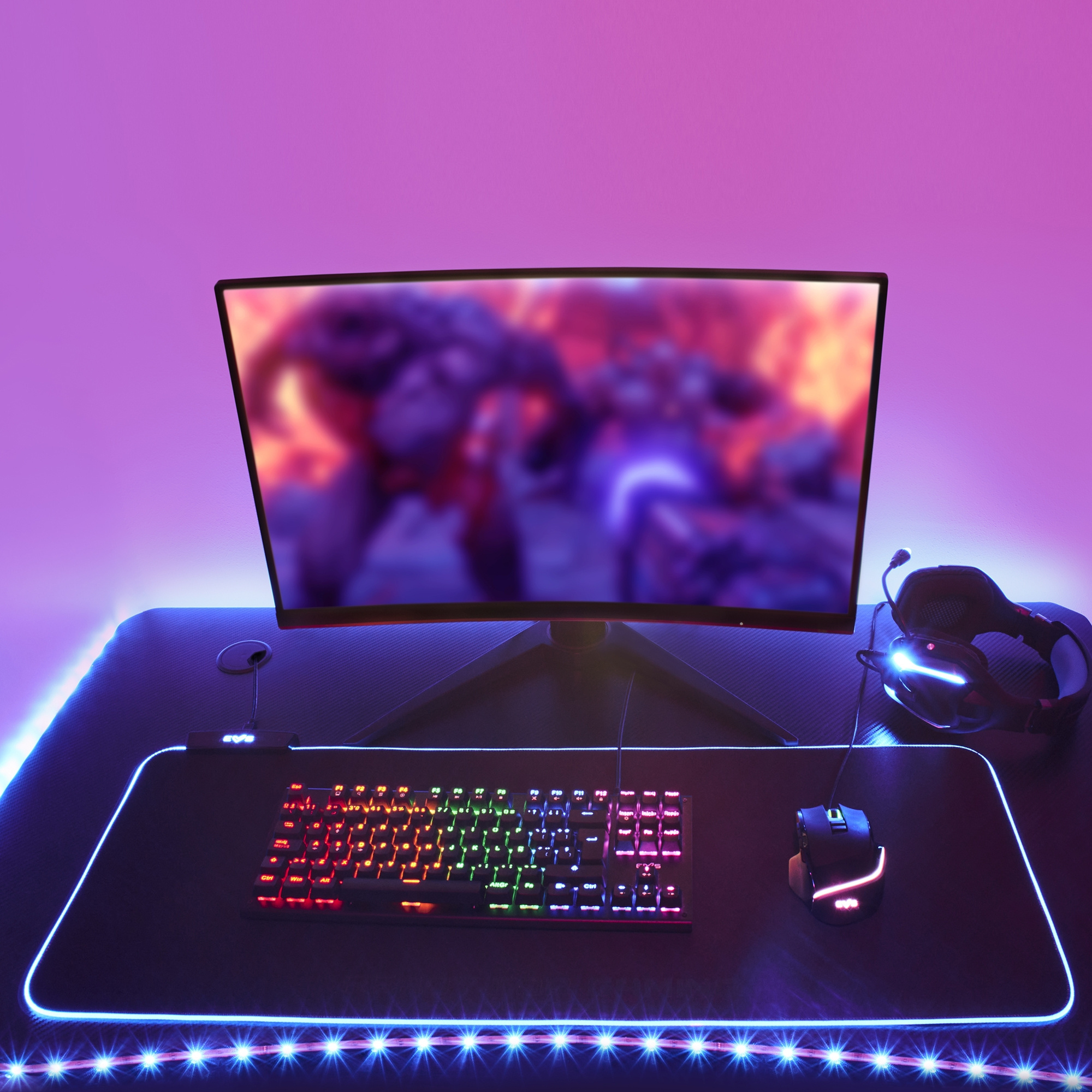 Configuración de juegos con monitor curvo, teclado, ratón, auriculares e iluminación RGB.