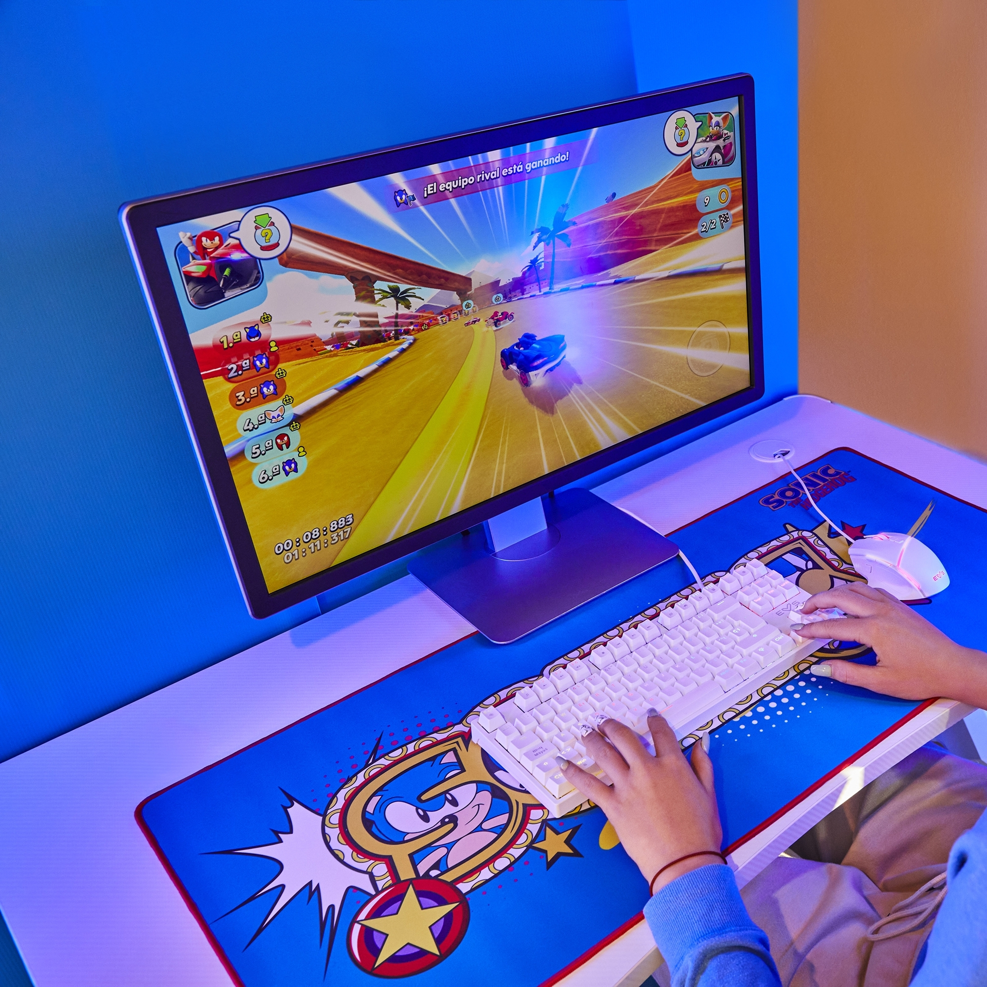 Osoba gra w grę wyścigową na monitorze komputera z klawiaturą i myszą.