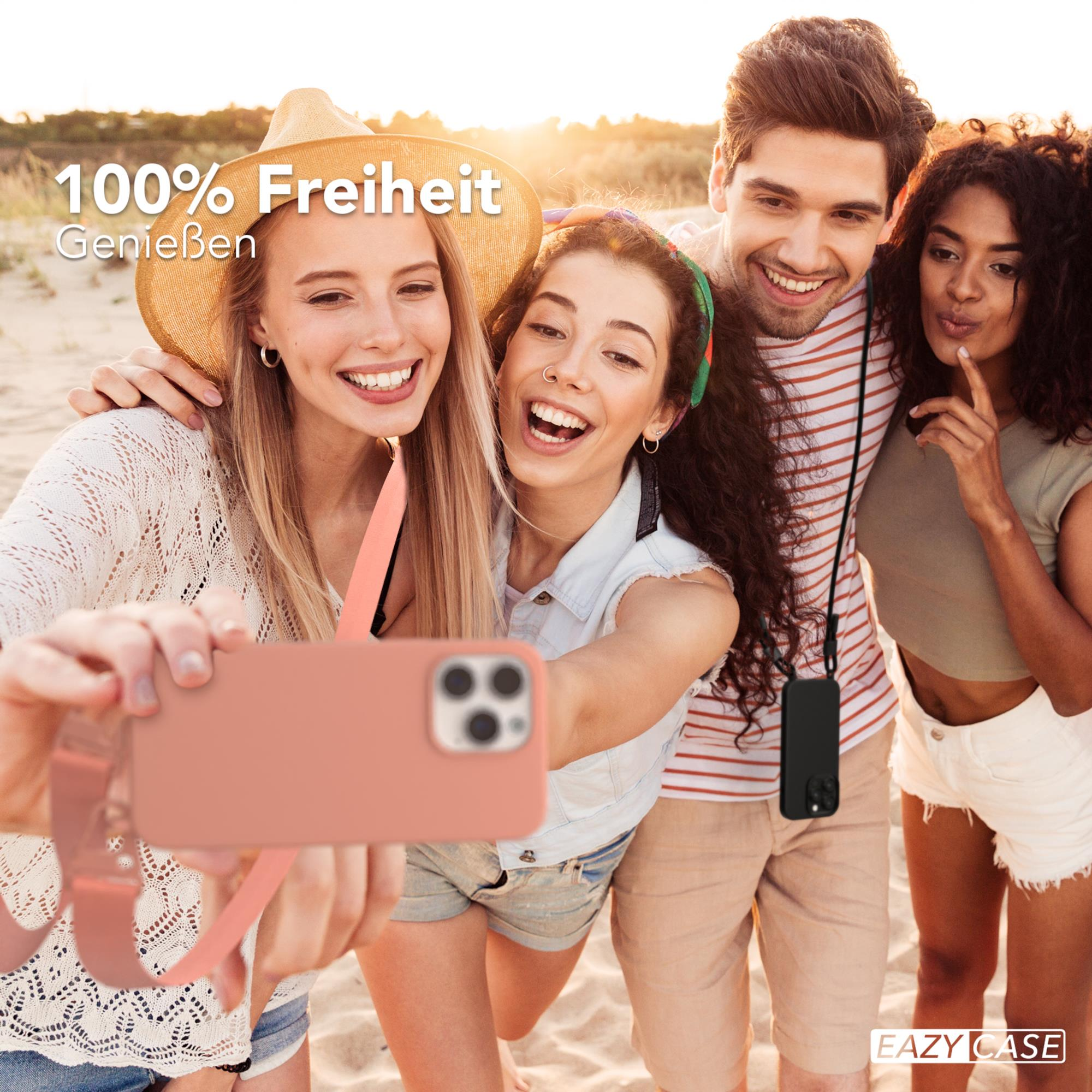 Vier Personen machen ein Selfie am Strand. Einer hält ein Telefon mit rosa Hülle. Sonniger Tag.