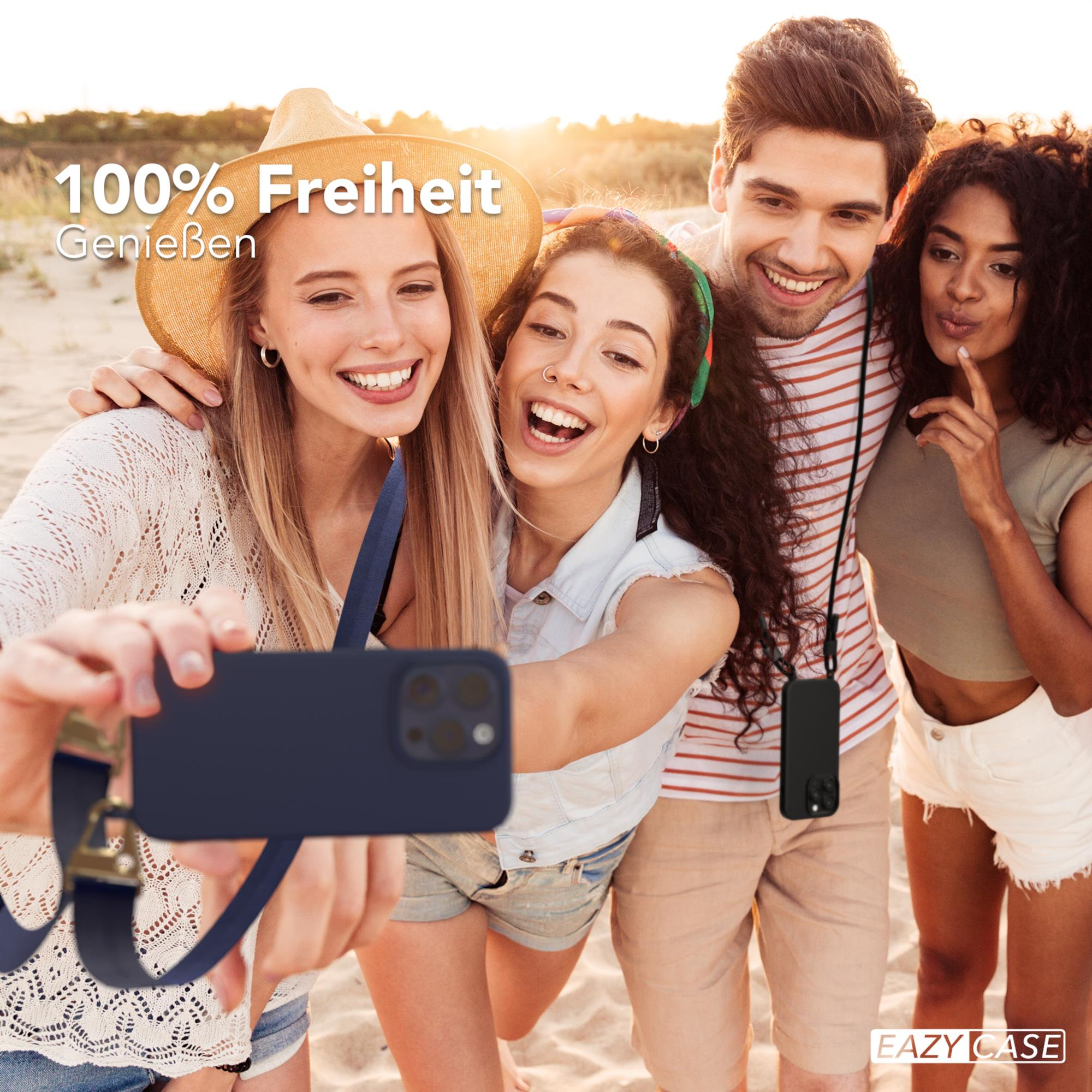 Vier Personen machen ein Selfie am Strand, zwei lächeln breit, eine andere berührt ihr Kinn.