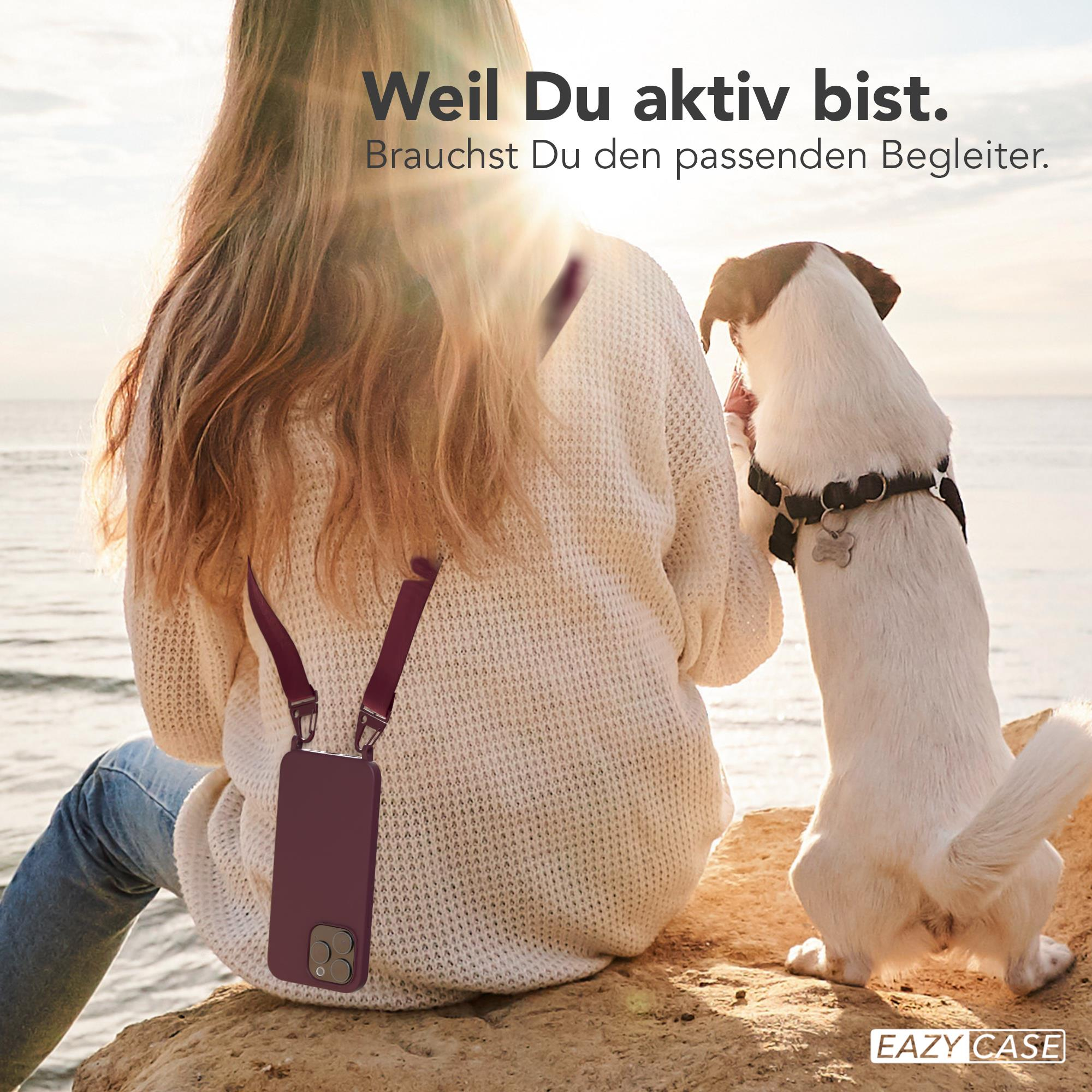 Eine Frau und ein Hund sind am Strand. Die Frau hält ein Telefon mit Hülle. Text auf Deutsch steht oben.