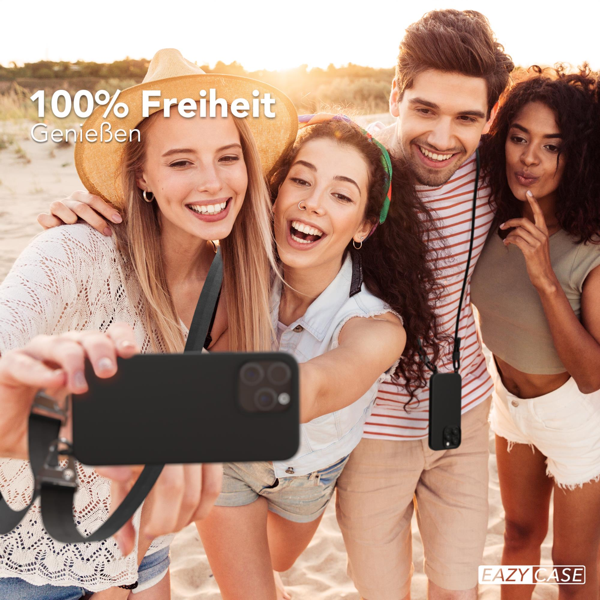 Vier Personen machen ein Selfie am Strand, halten ein Telefon mit schwarzer Hülle.