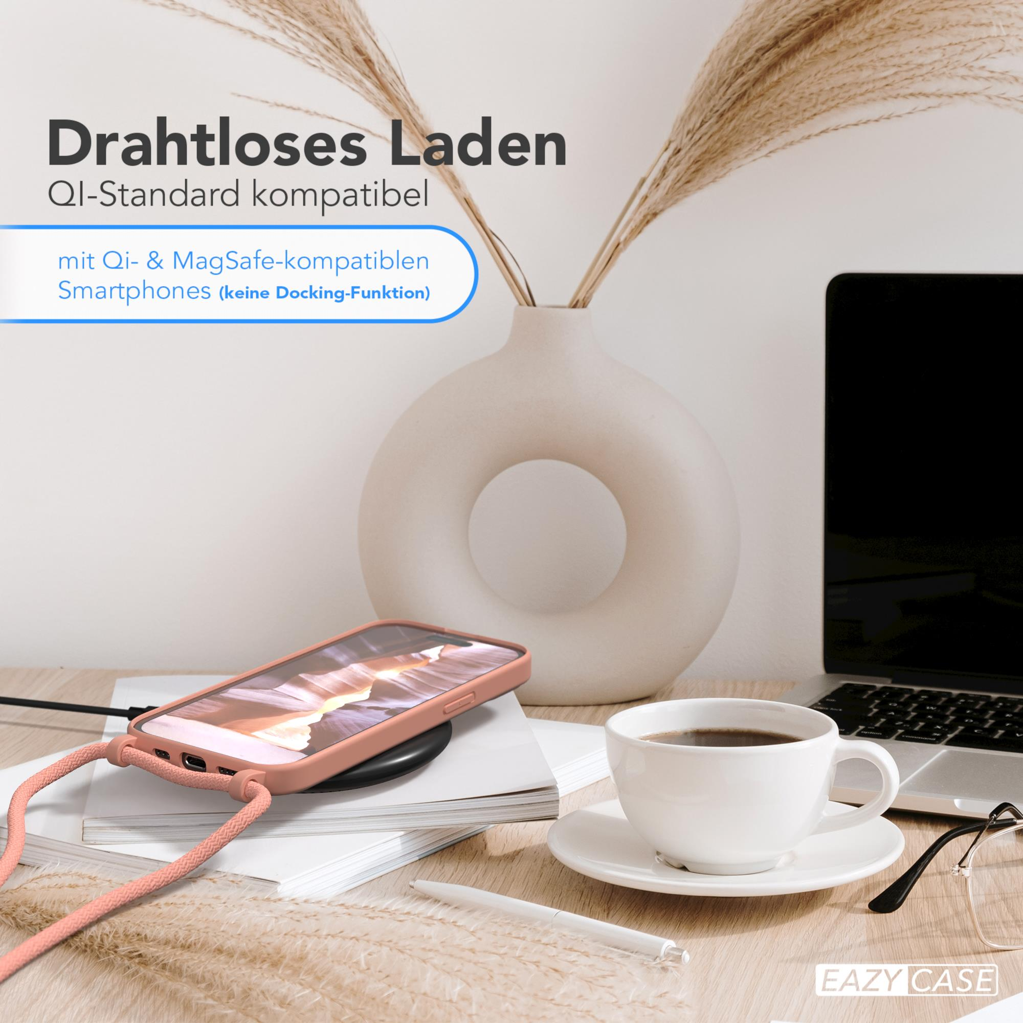 Telefon lädt auf schwarzem Pad. Weiße Vase, Kaffeetasse, Laptop und Papier auf dem Tisch.