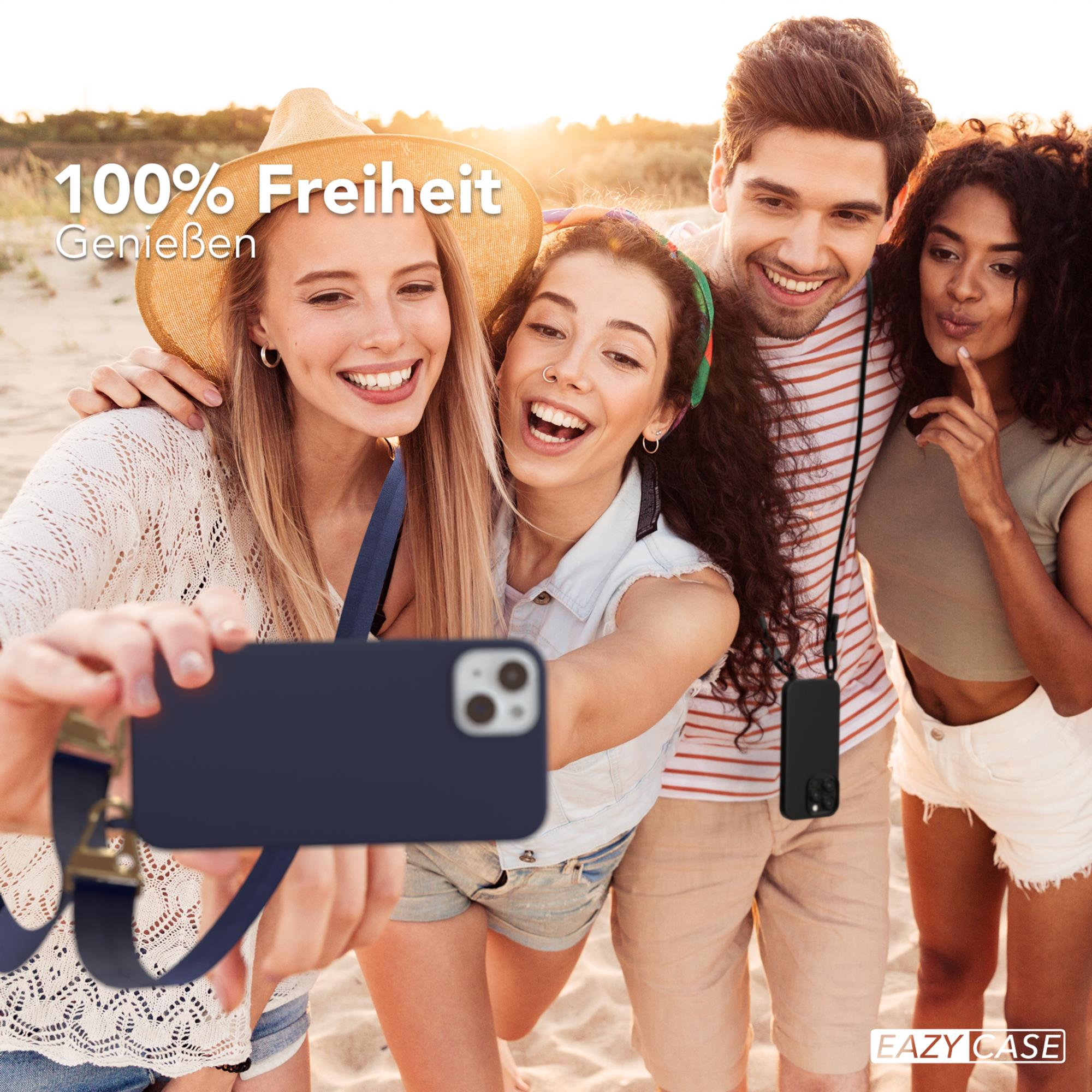 Vier lächelnde Personen halten ein Telefon mit blauer Hülle für ein Selfie am Strand.