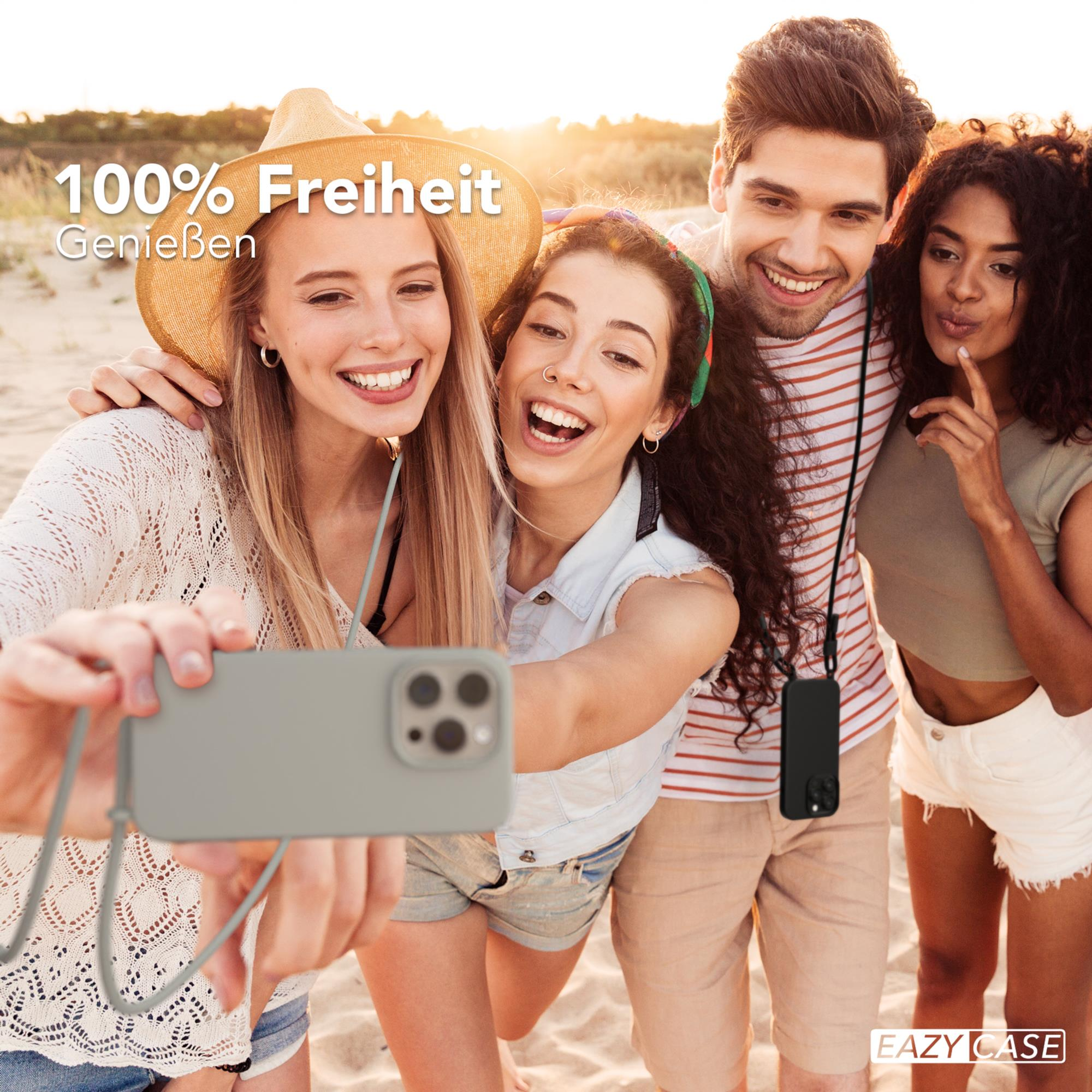 Freundesgruppe macht Selfie am Strand, hält Telefon mit Gurt.