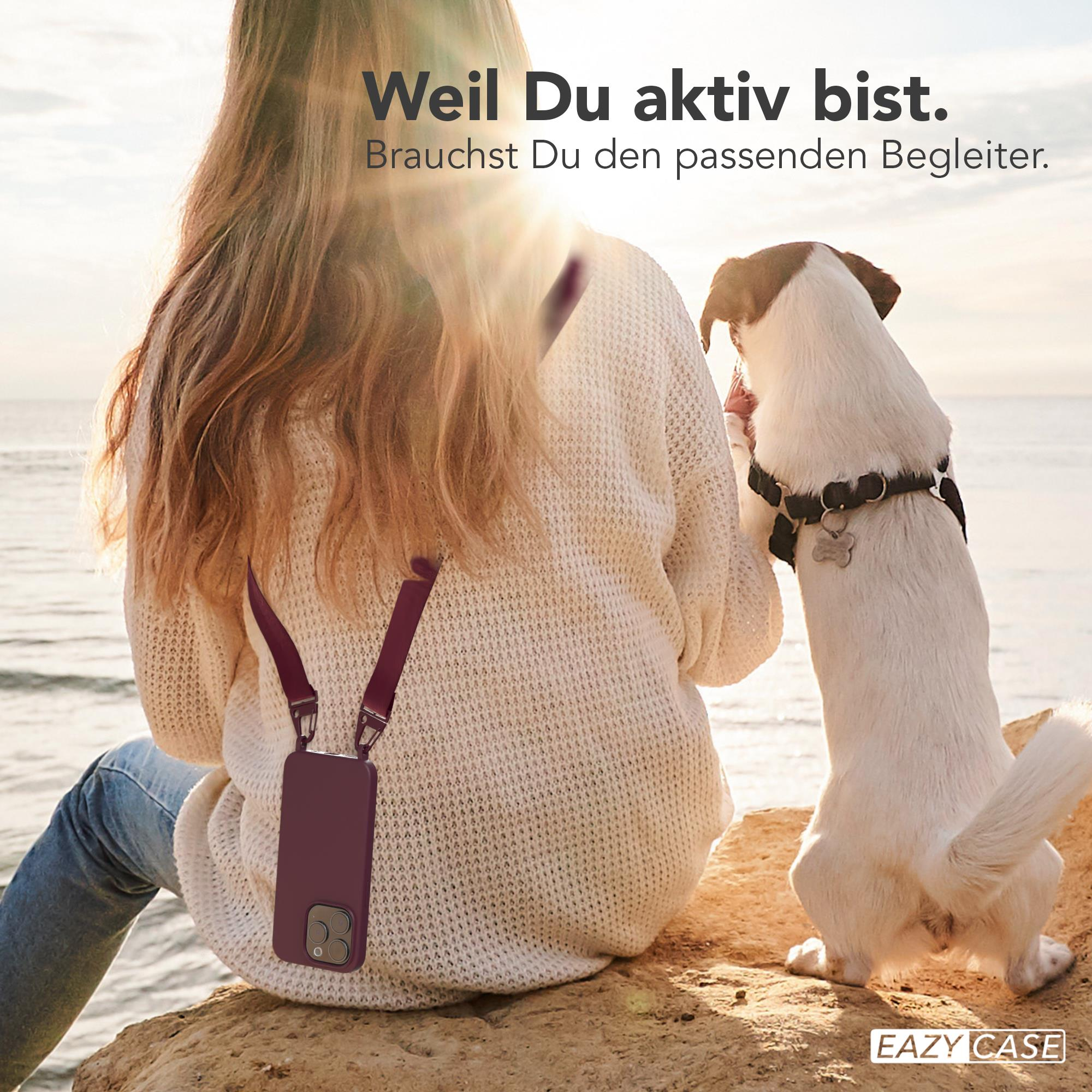 Frau mit Handyhülle und Gurt sitzt mit Hund beim Sonnenuntergang.