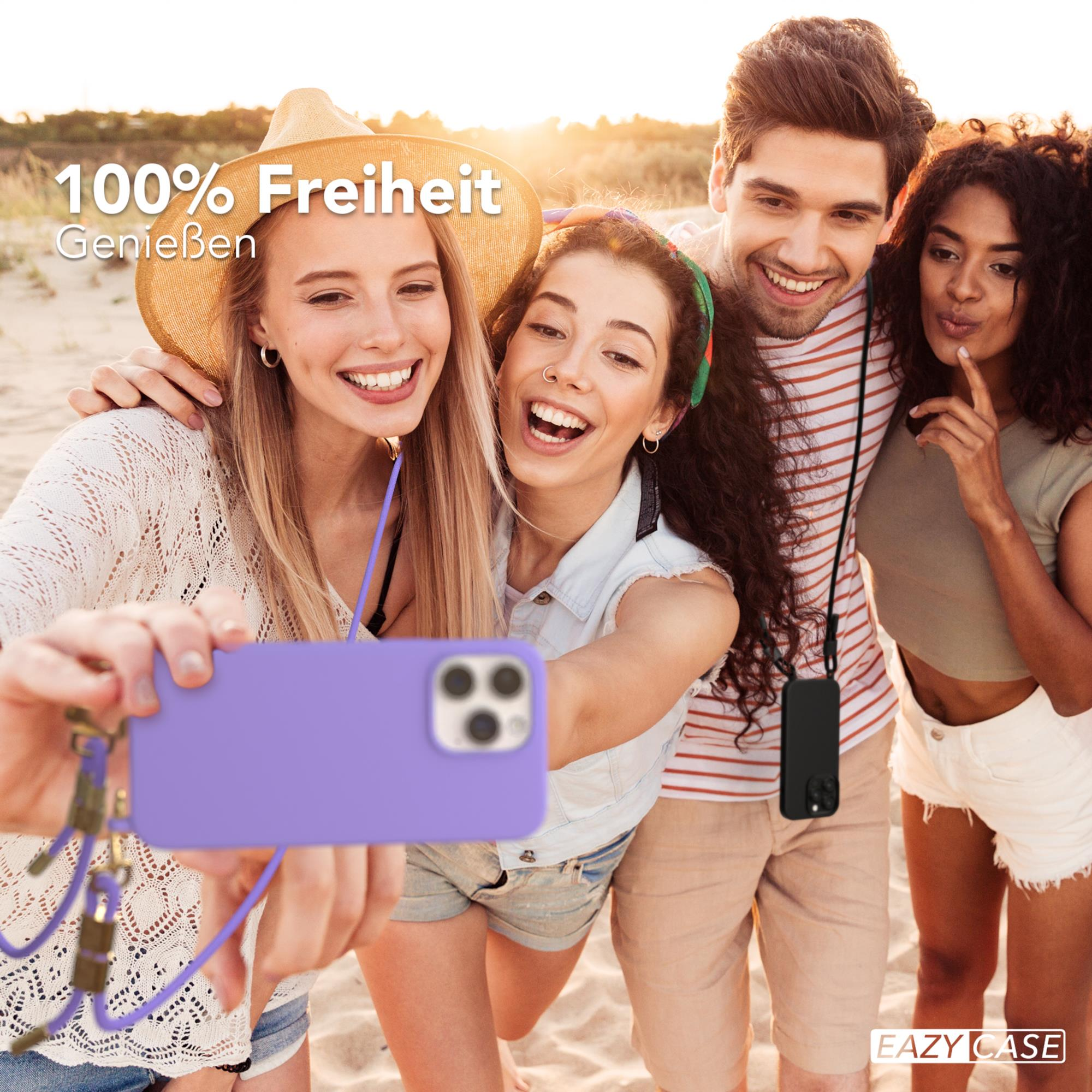 Vier Personen machen ein Selfie mit einer lila Handyhülle am Strand, lächeln und lachen.
