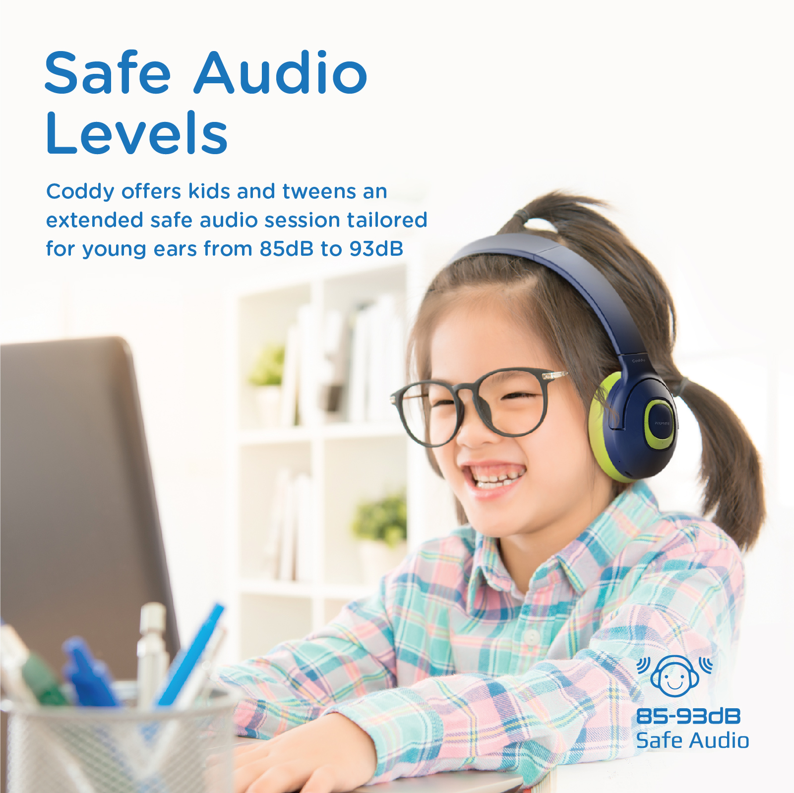 Niña con gafas usando auriculares. Los auriculares son azules y verdes. Portátil frente a ella.