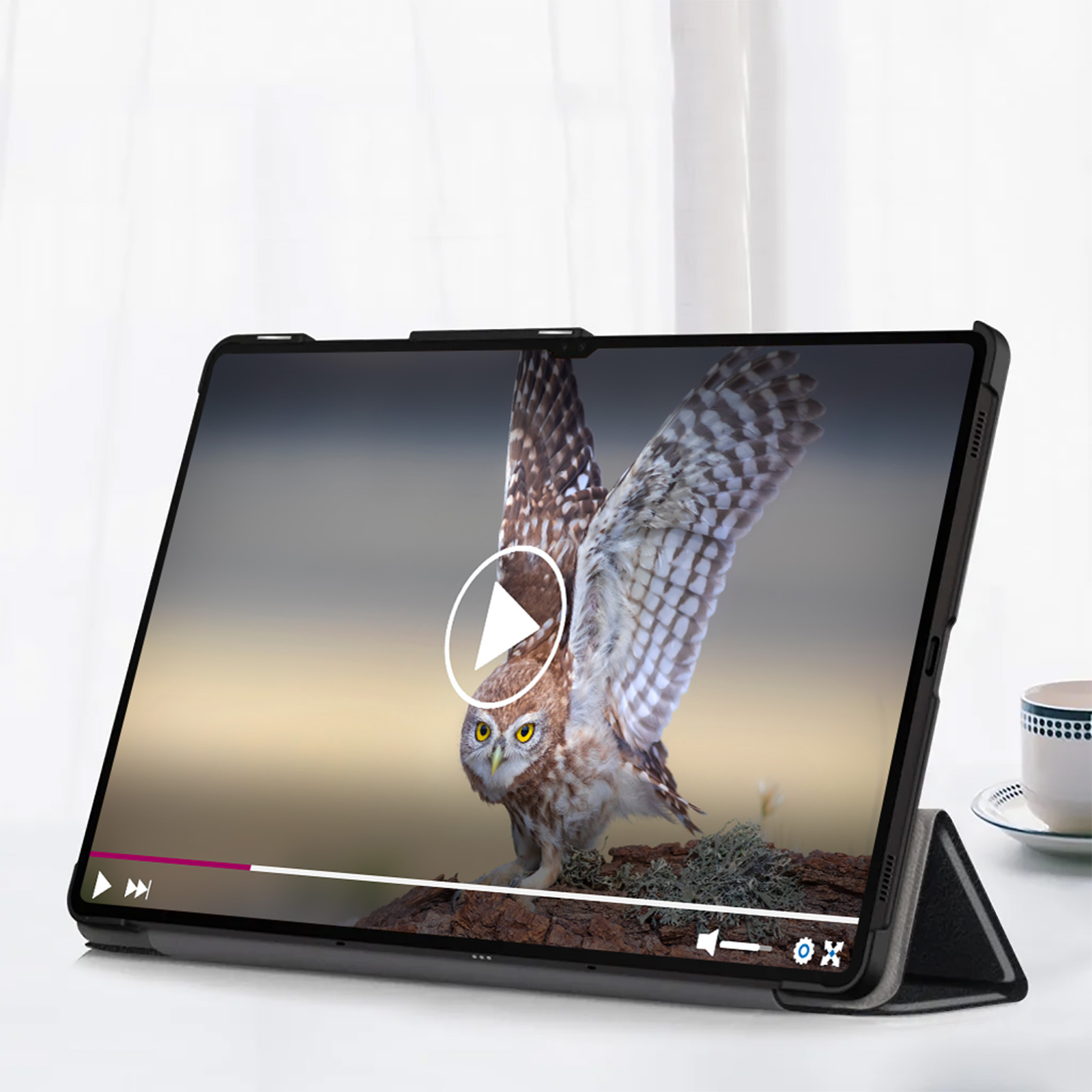 Tablet che mostra un video di un gufo. Il tablet è in una custodia. Una tazza è sullo sfondo.