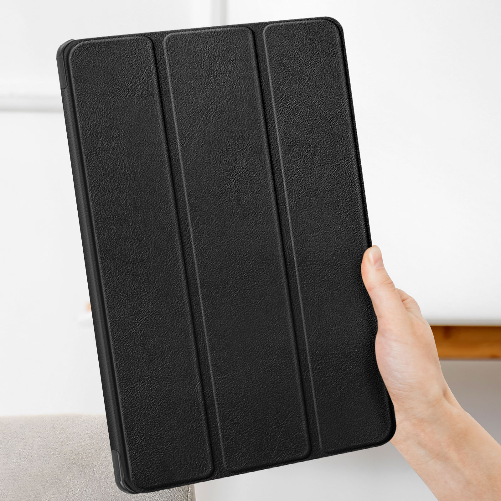 Una custodia nera per tablet tenuta da una mano. La custodia è chiusa e strutturata.