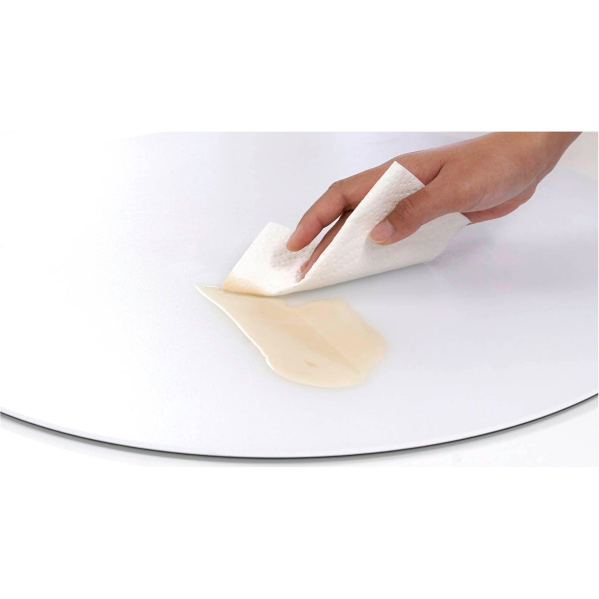 Mano limpiando un derrame en una superficie blanca con papel de cocina.