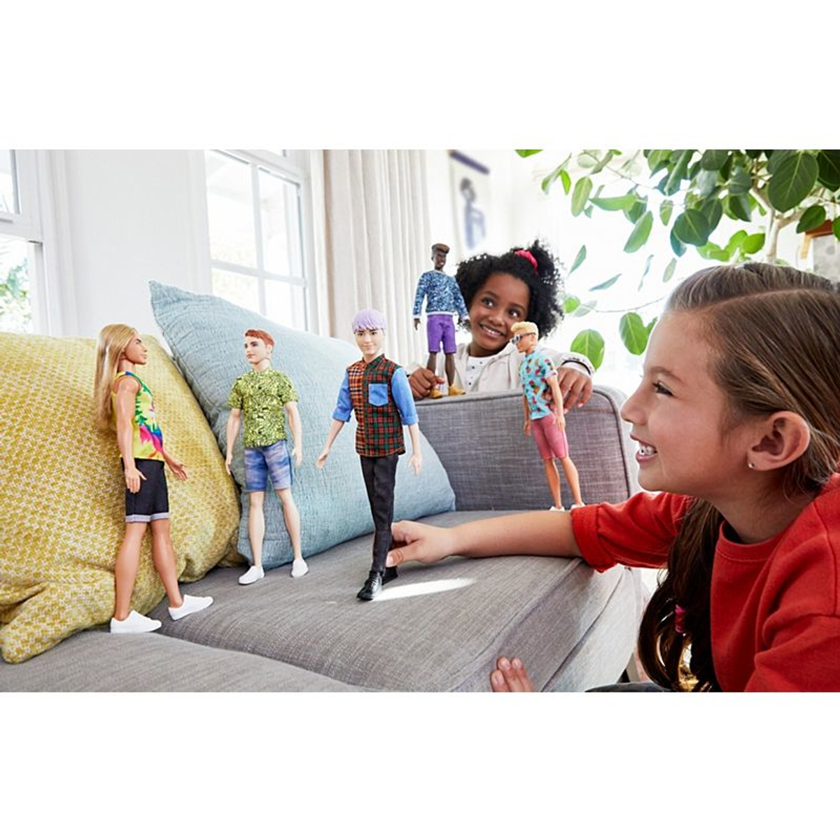 Kinder mit Puppen auf einem Sofa. Mehrere Puppen verschiedener Ethnien.