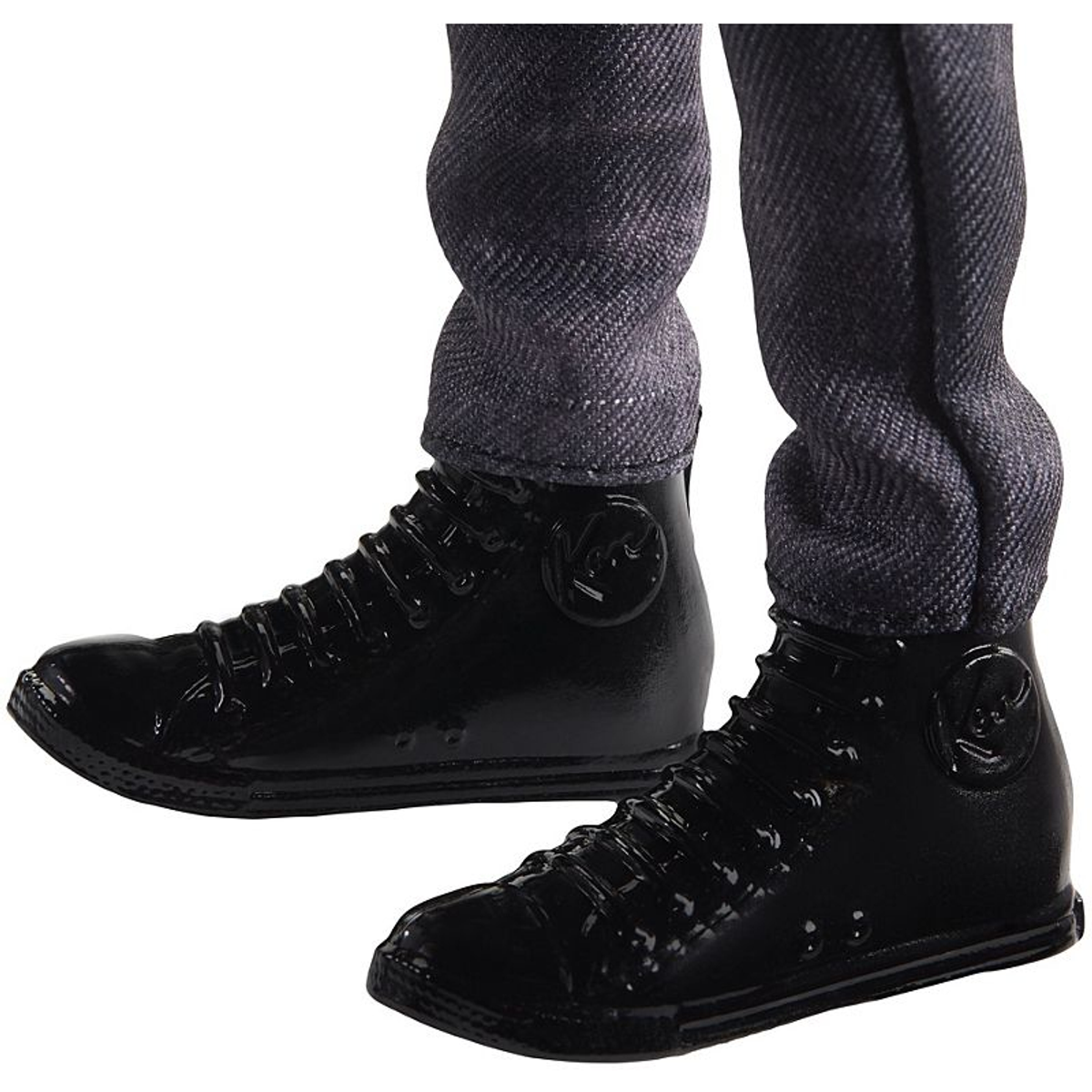 Beine einer Person in grauer Hose und schwarzen Lacklederschuhen. Die Schuhe sind glänzend und haben ein Logo an der Seite.