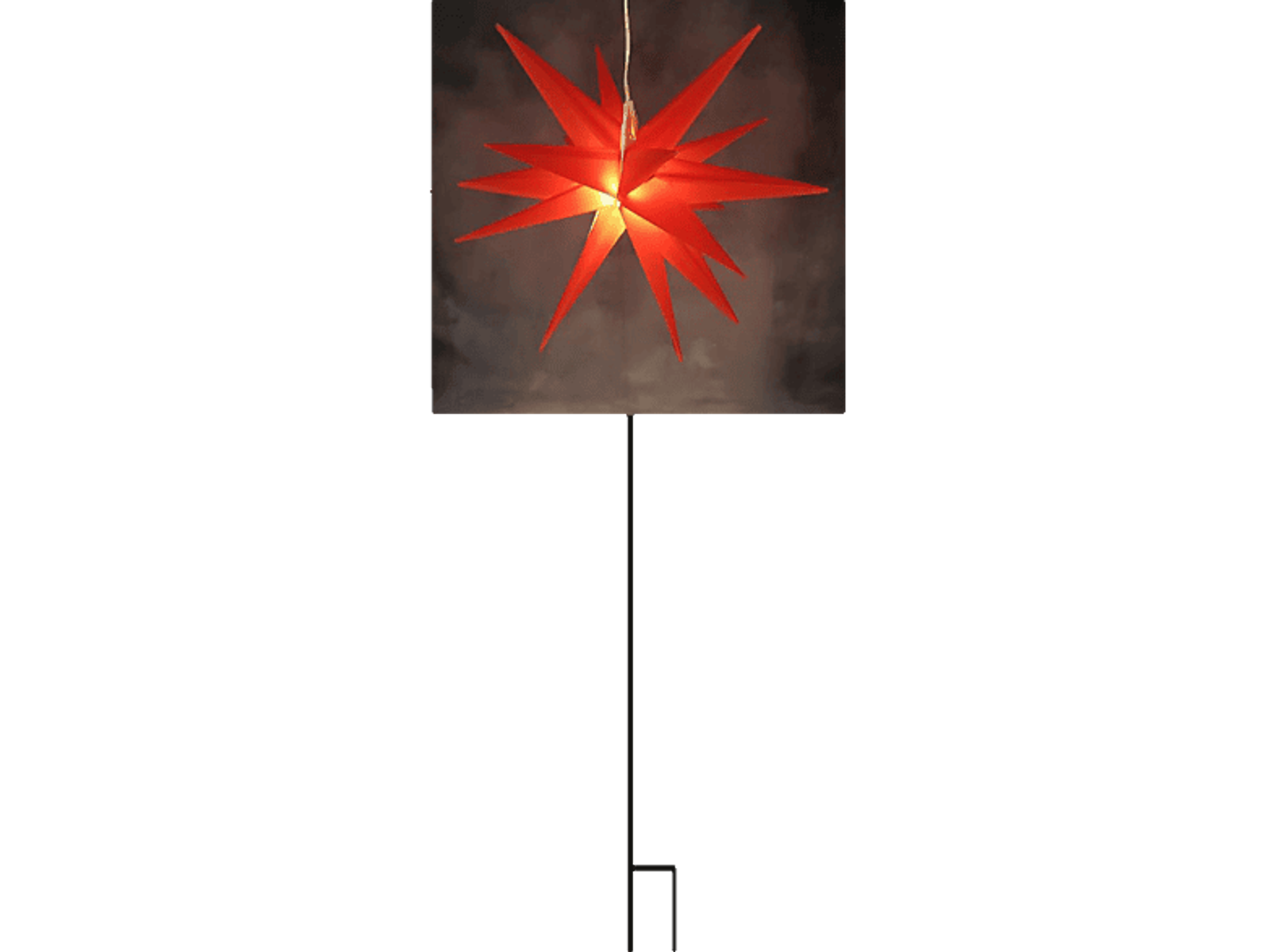 Roter sternförmiger Weihnachtsschmuck, der vor dunklem Hintergrund hängt. Ein Licht ist an.