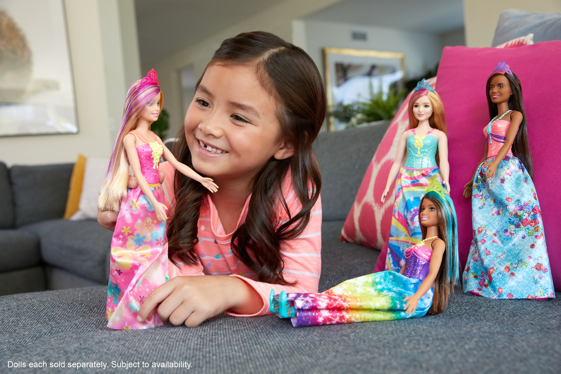 Ein Kind lächelt mit Barbie-Puppen. Fünf Puppen werden gezeigt, in verschiedenen Stilen und Kleidern.