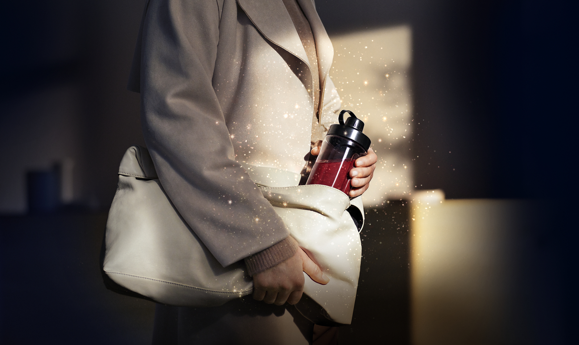 Eine Person hält eine Tasche mit einem roten Behälter, mit Glitzerlichtern im Hintergrund.