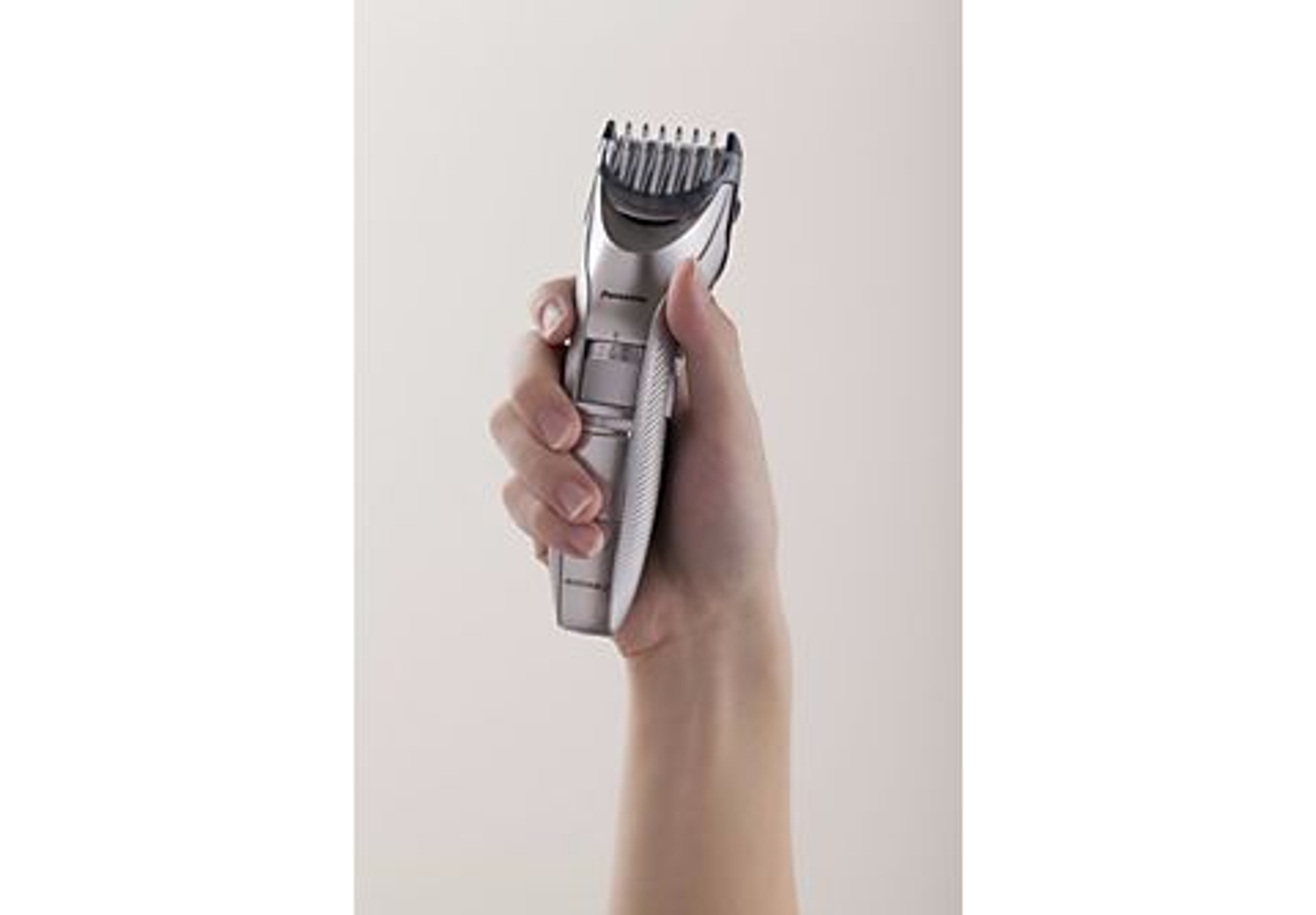 Hand, die einen silbernen Haarschneider hält.
