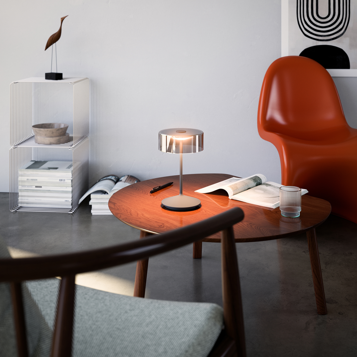 Wohnzimmer mit Lampe auf Tisch, Stuhl und Büchern. Holztisch, weiße Wände.