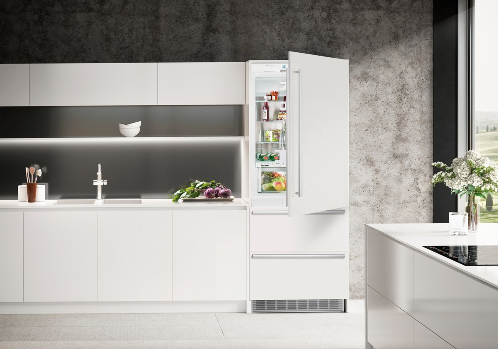 Una cucina moderna con mobili bianchi aperti e un frigorifero. La porta del frigorifero è aperta.