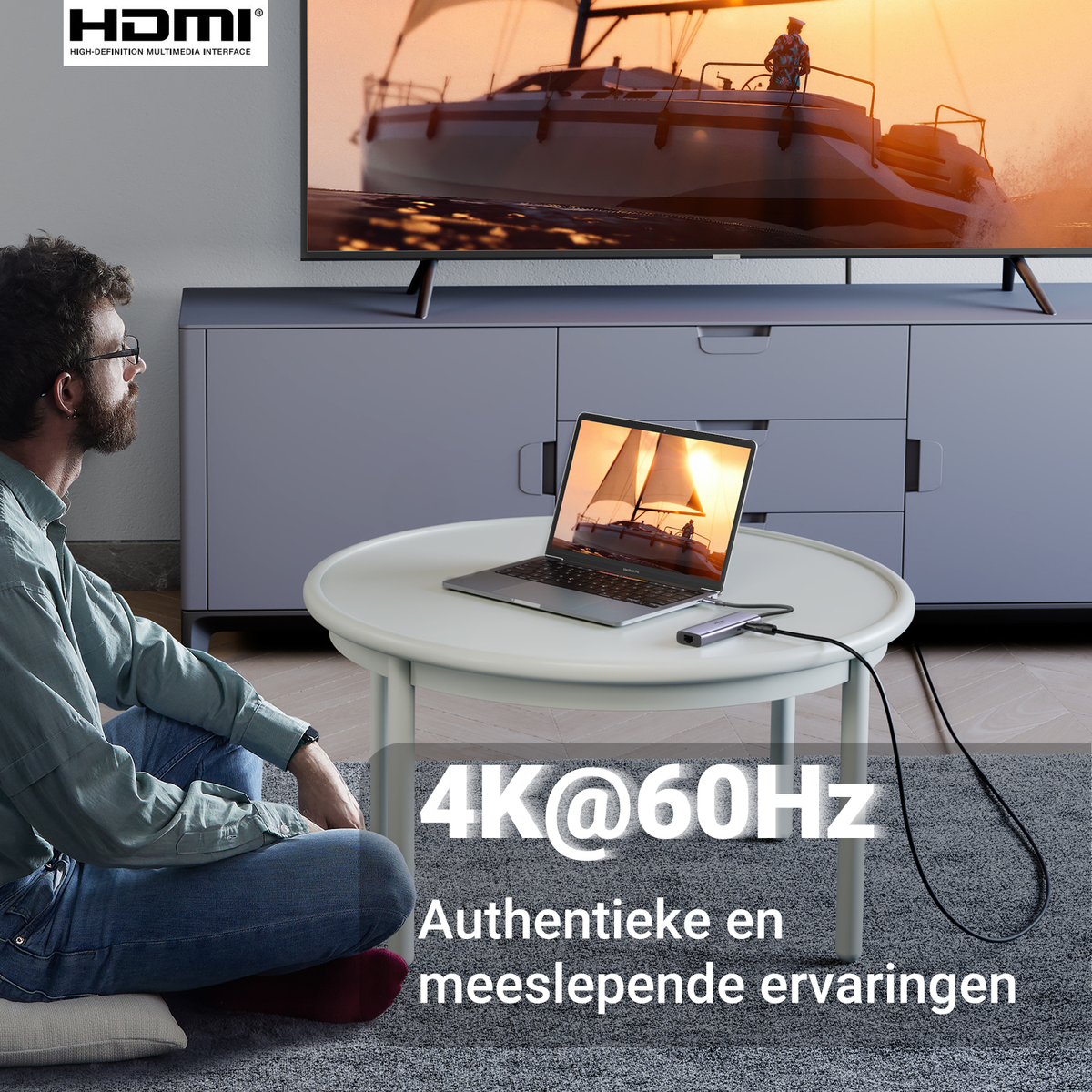 Un hombre mira un portátil conectado a un televisor, con texto 4K@60Hz.