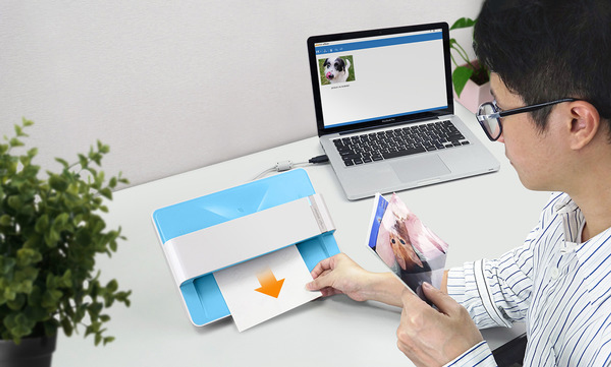 Mężczyzna używa drukarki, drukuje zdjęcie z laptopa. Niebiesko-biała drukarka na biurku.