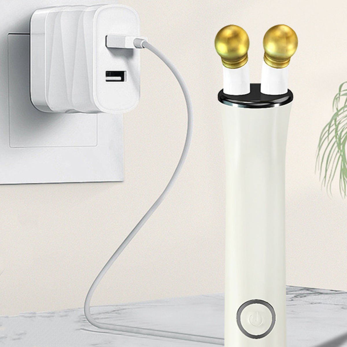 Ein weißes Ladegerät mit zwei goldfarbenen Aufsätzen und einem USB-Kabel, das in der Wand steckt.
