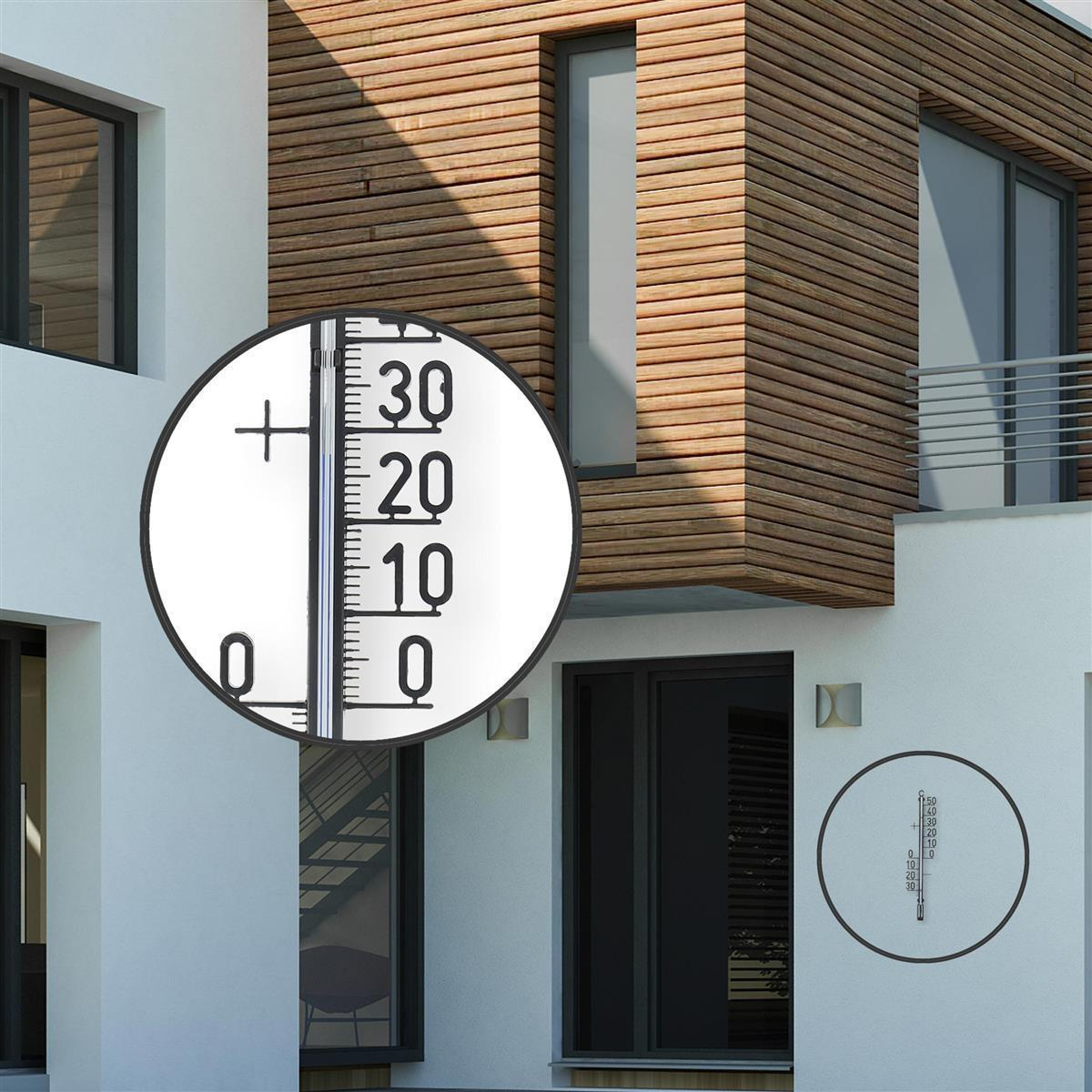 Nahaufnahme eines Thermometers, ein Gebäude mit Holzfassade.