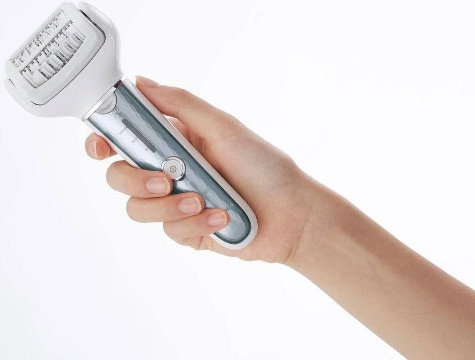 Una mano tiene un epilatore elettrico con corpo bianco e verde acqua su sfondo bianco.