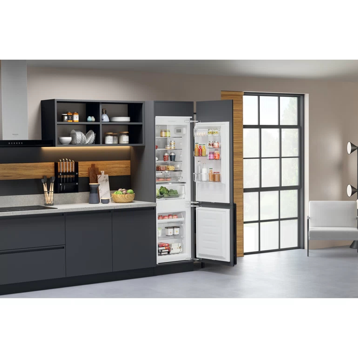 Eine Küche mit dunklen Schränken, einem Kühlschrank mit offenen Türen und einem Fenster.