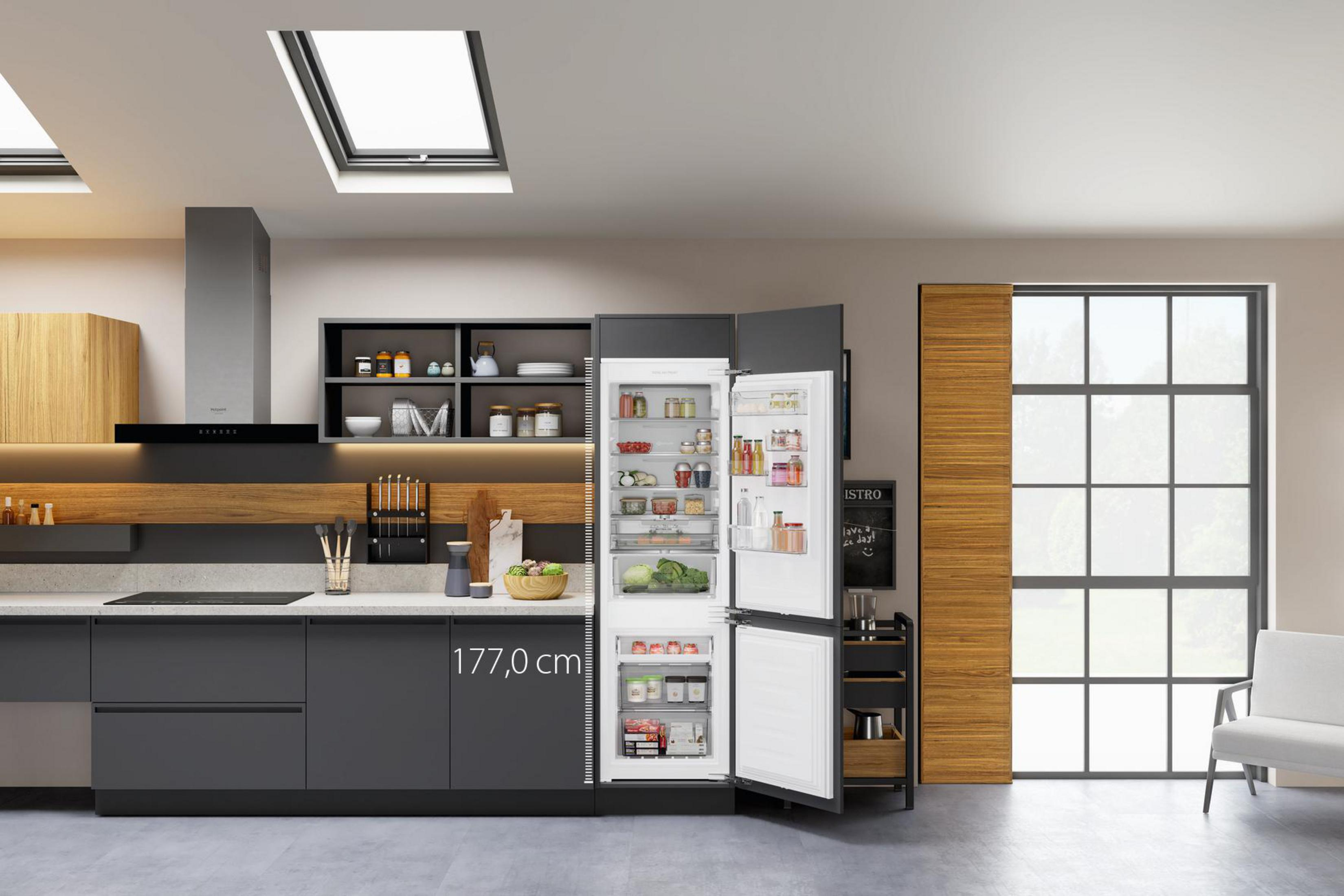 Moderne Küche mit dunkelgrauen Schränken, offenem Kühlschrank mit Lebensmitteln und Oberlicht.